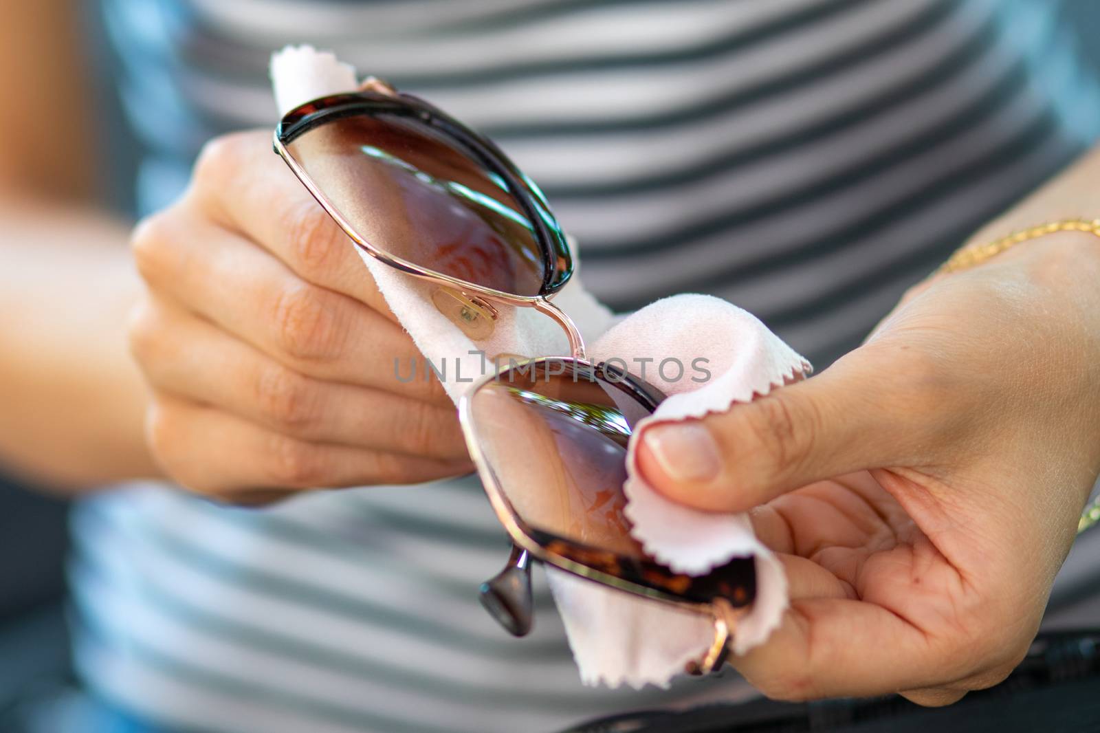 Wiping sunglasses - Woman cleaning sun glasses with micro fiber  by adamr