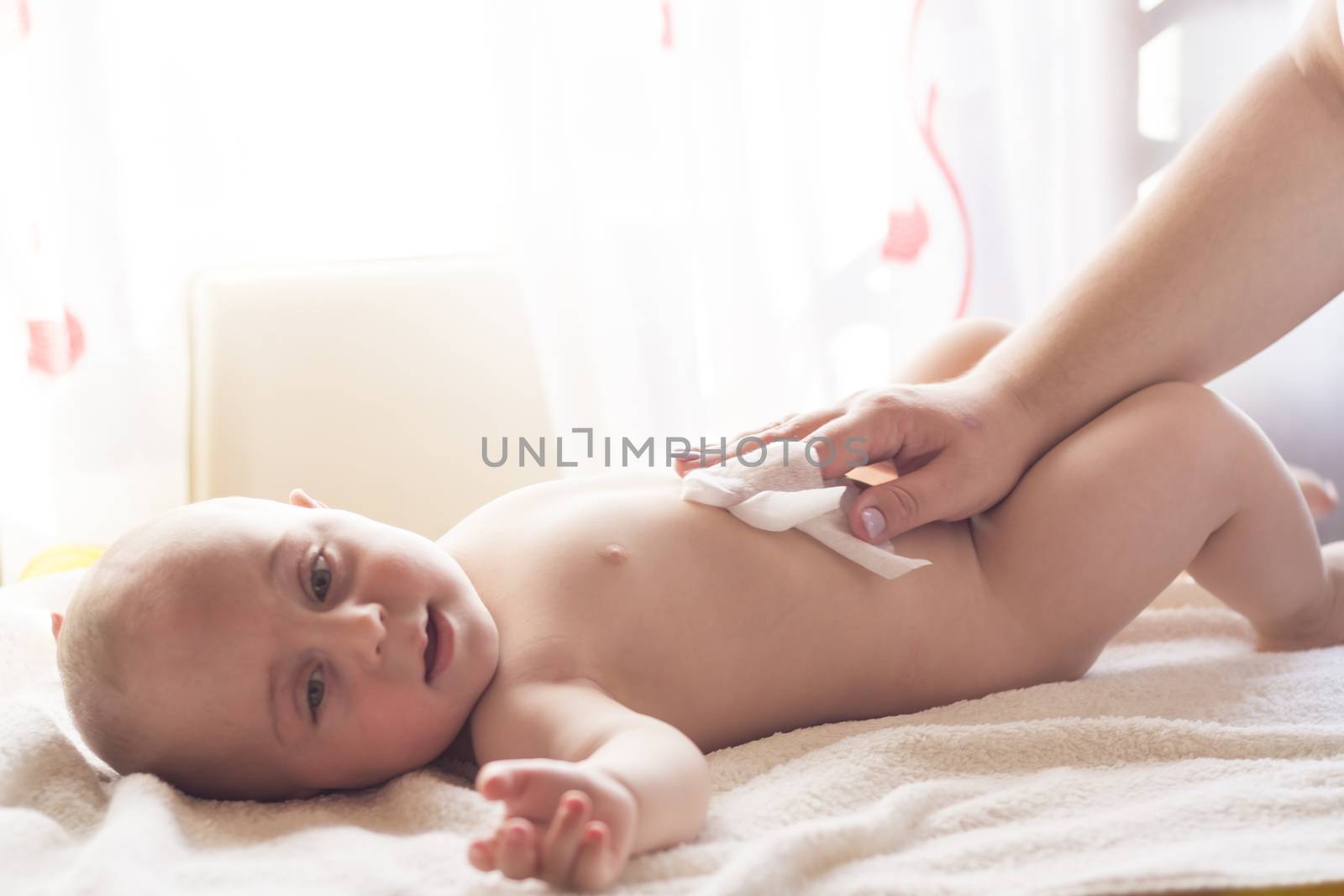 Hygiene - young mom wiping the baby skin with wet wipes carefully. Cleaning wipe, pure, clean