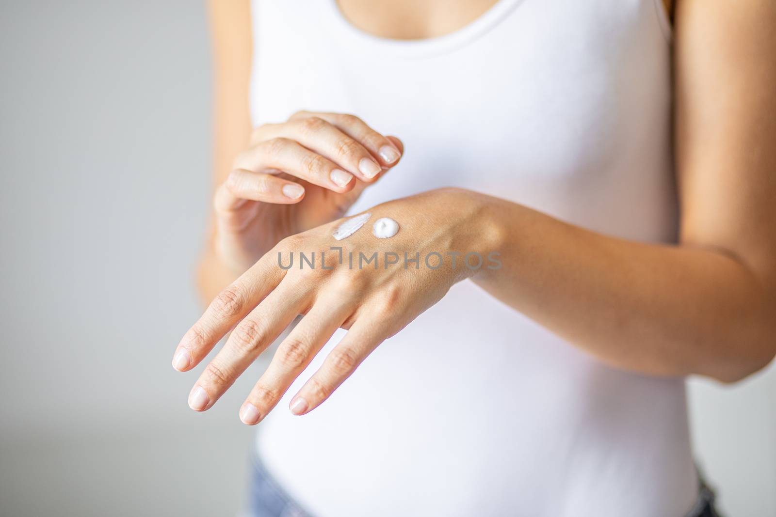 Young woman applying hand cream to care and protect skin, close up.