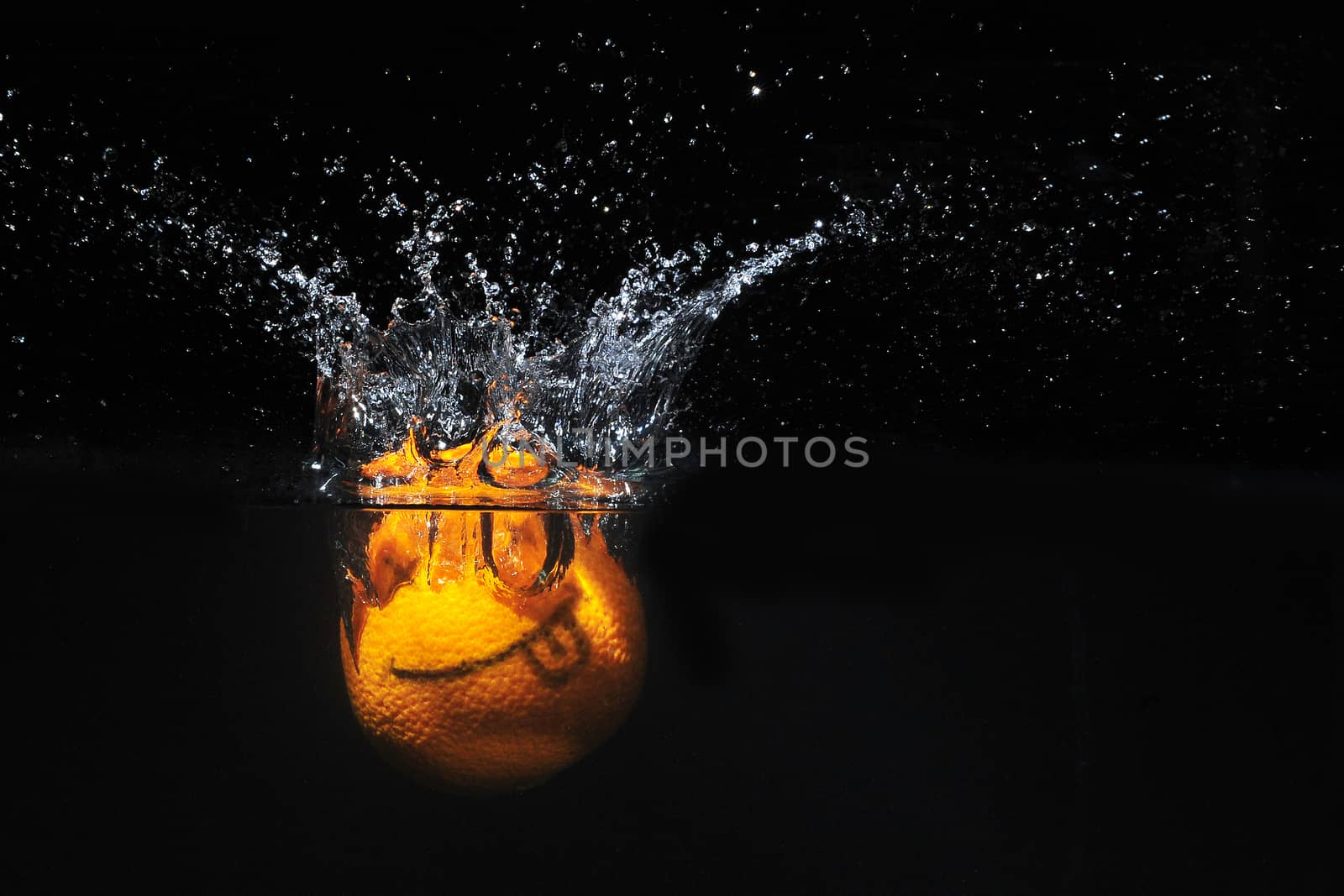 Smile orange with splashes of water on a black background