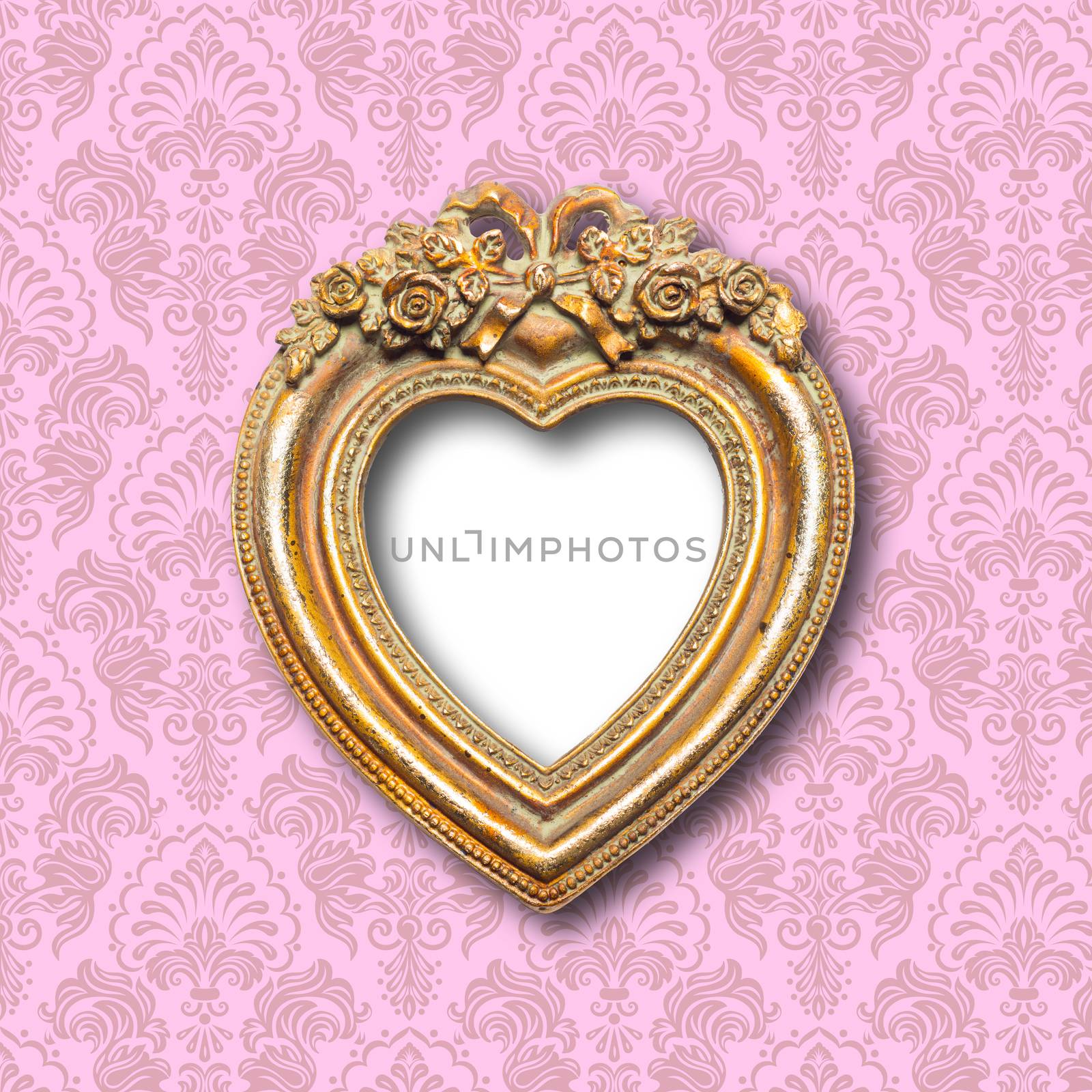 Old gold ornamental heart shape picture frame on pattern wall