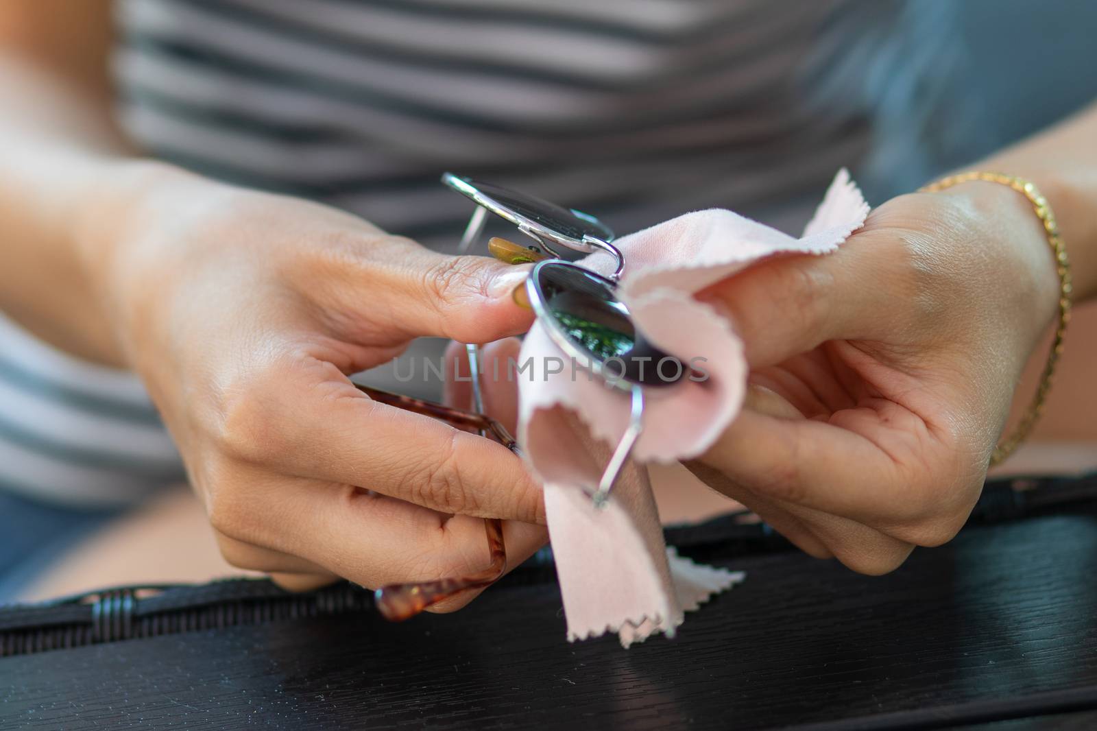 Woman hands cleaning sun glasses with micro fiber wipe by adamr