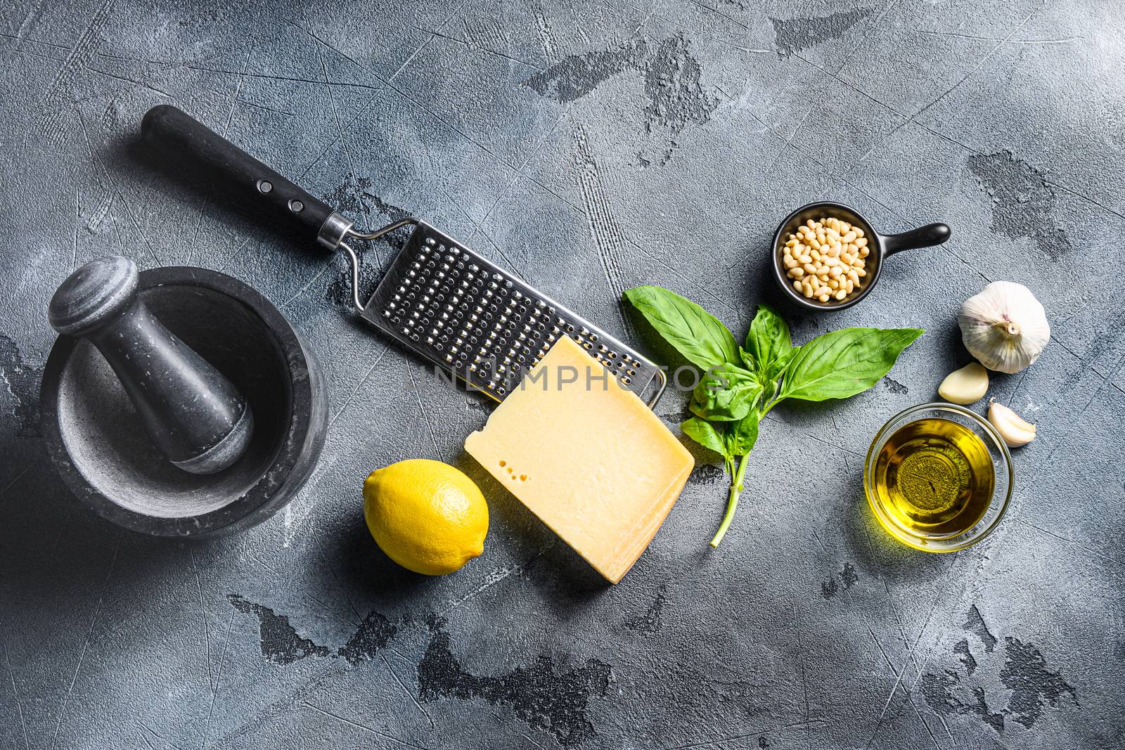 Pesto Ingredients italian recipe Fresh basil, tomatoes mortar lemon olive oil parmesan pine nuts on the stone table on gray concrete background Top view by Ilianesolenyi