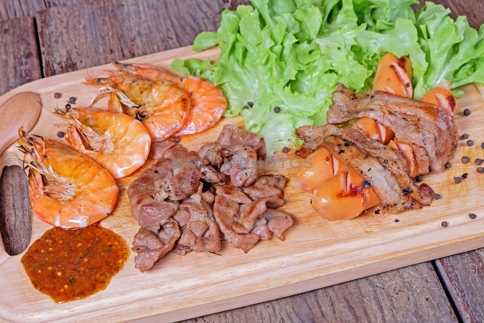 Grilled meat and shrimps with vegetables, barbecue grill food on wood background