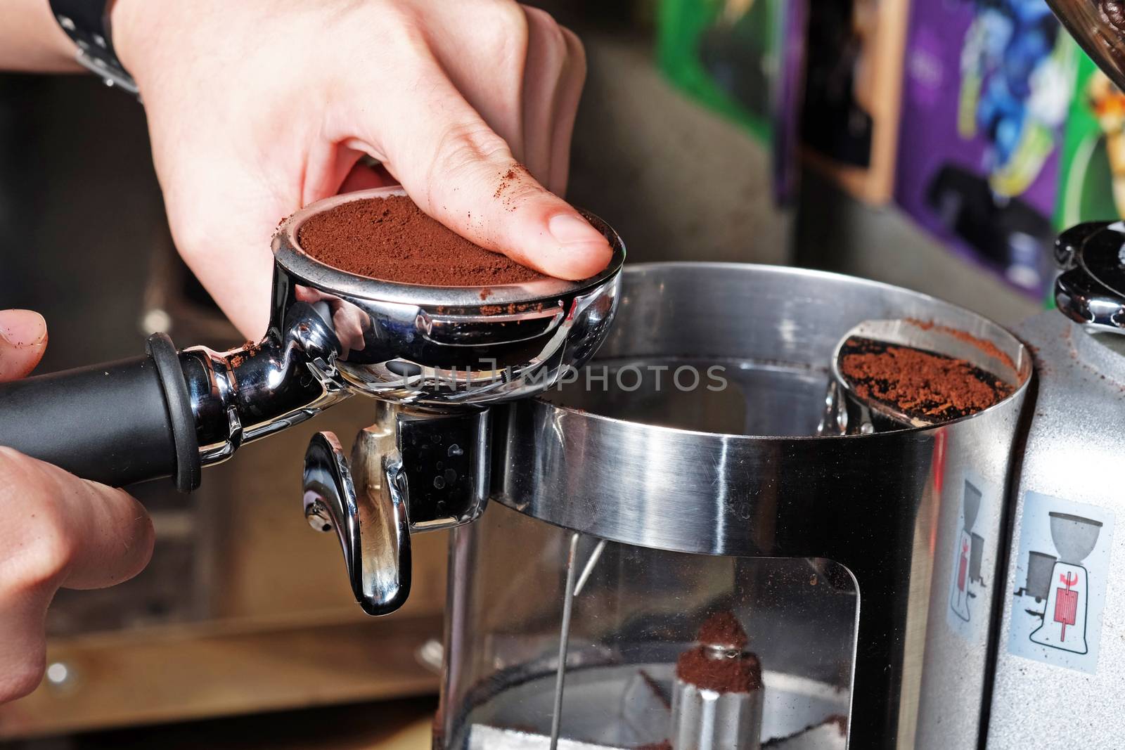 Barista compresses coffee grounds with tamper by Surasak