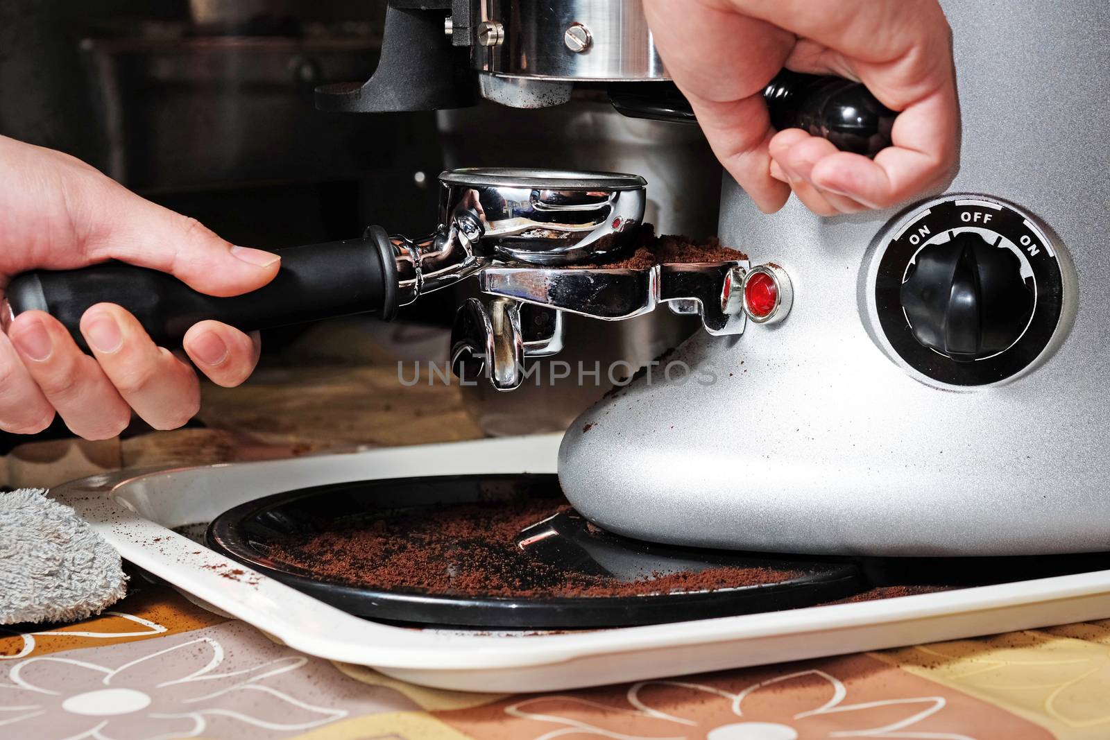 Barista compresses coffee grounds with tamper by Surasak