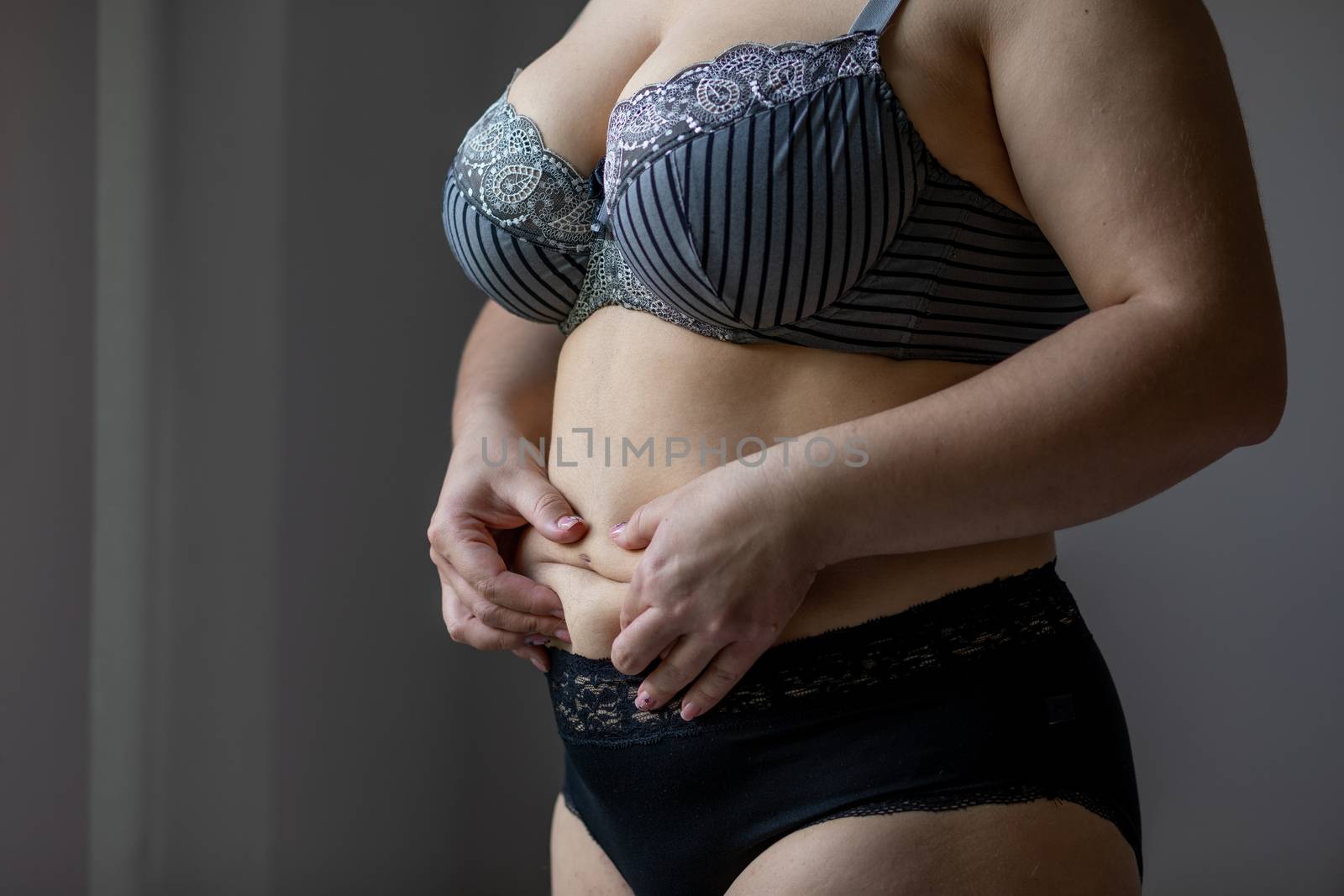 Woman Real Body Plus size Model in lingerie posign and touching fat on stomach, imperfect nonideal