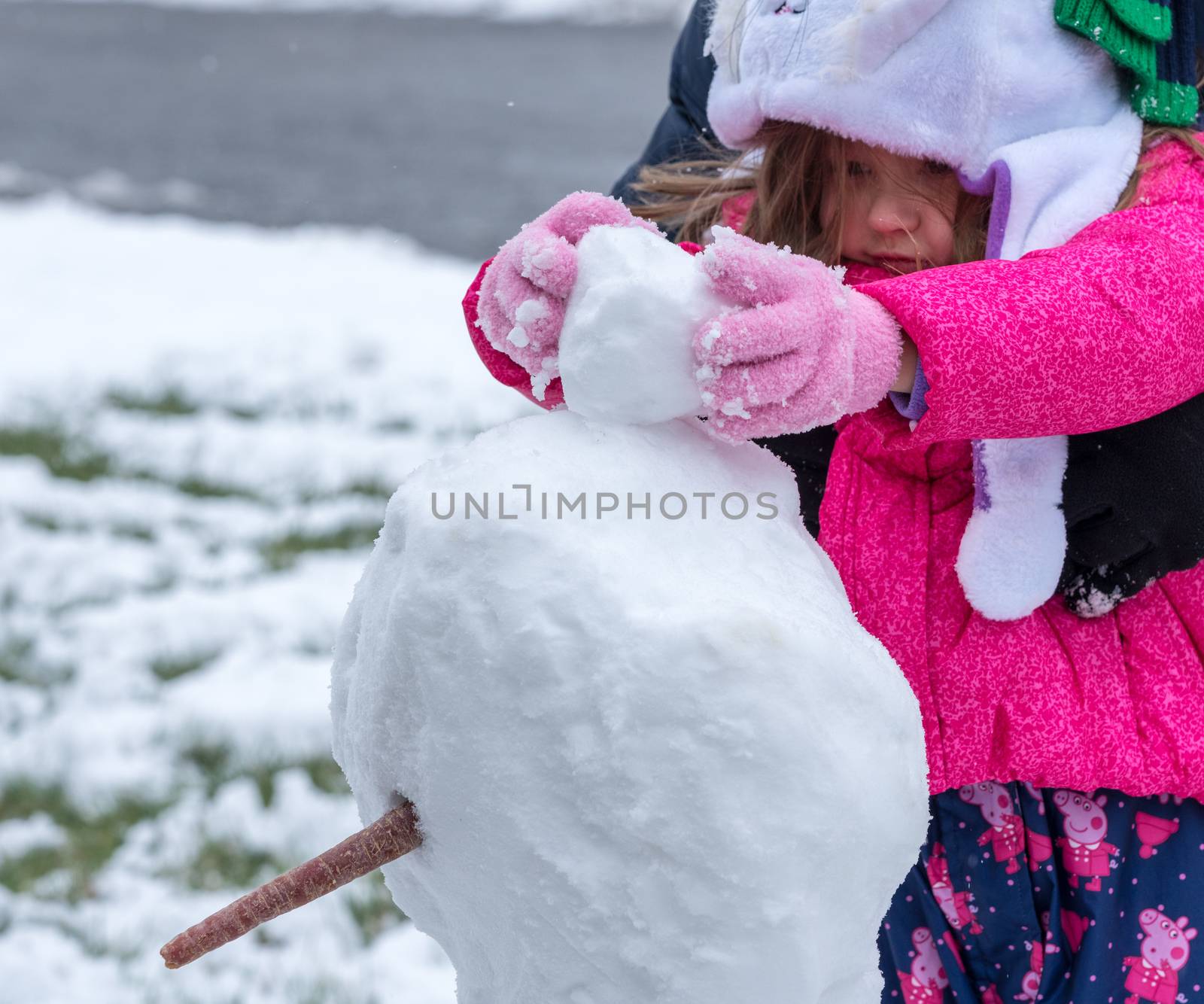 Toddler girl playing in the snow in front garden by steheap