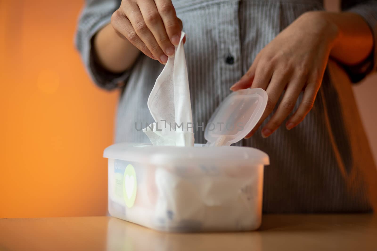 Wet wipes are universal an practical: woman hand take one wipe from big plastic box package for cleaning, home, indoor