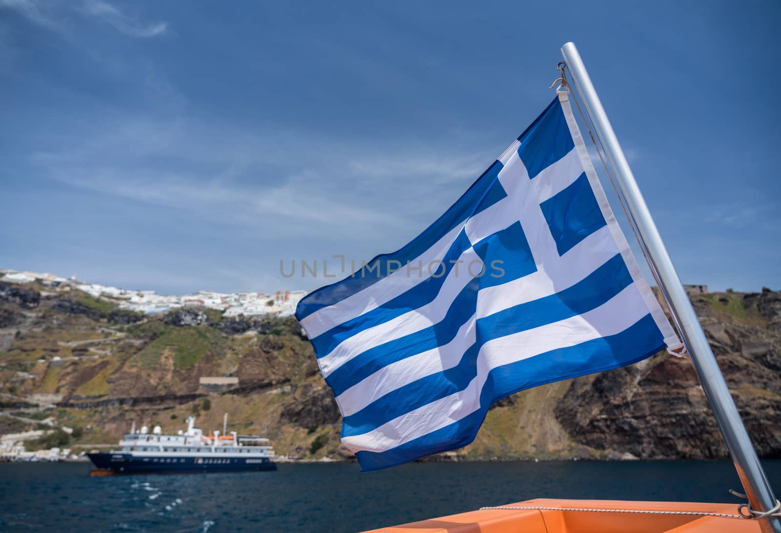 Greek flag on tender boat leaving Fira port on Santorini