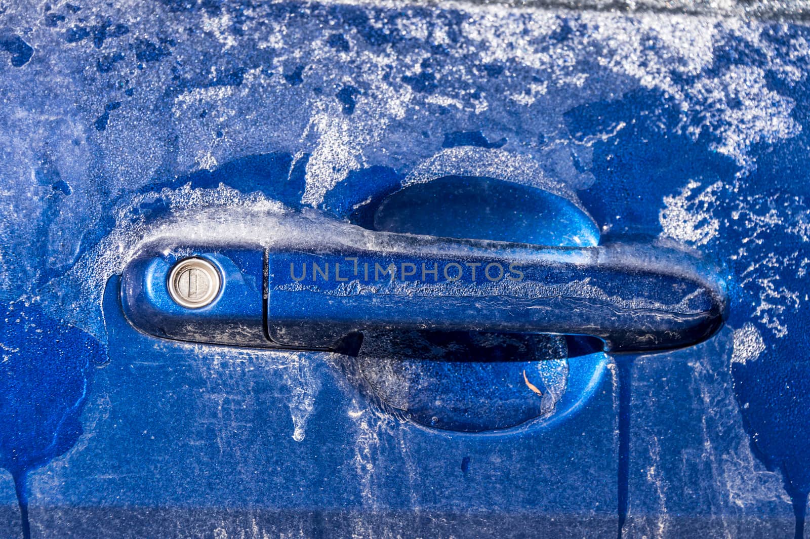 Thick layer of ice covering car after freezing rain in Montreal, Canada - Close up of car handle.