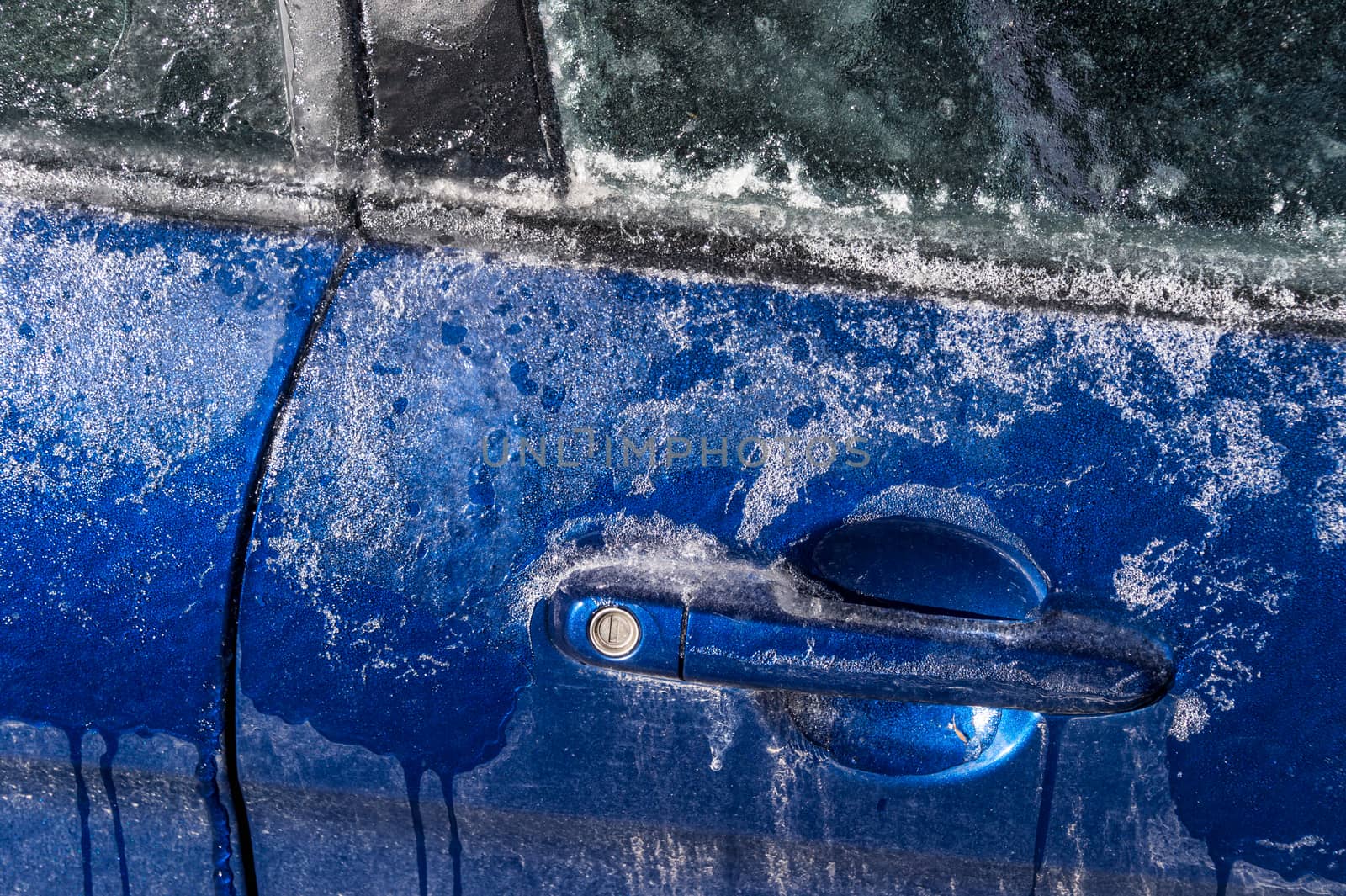 Thick layer of ice covering car after freezing rain in Montreal, Canada - Close up of car handle.