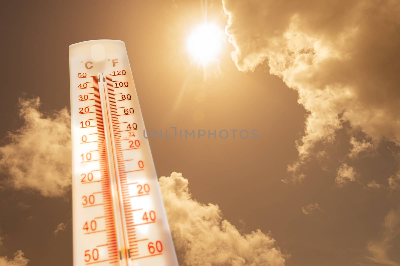 Thermometer in front of a sky with sun and clouds