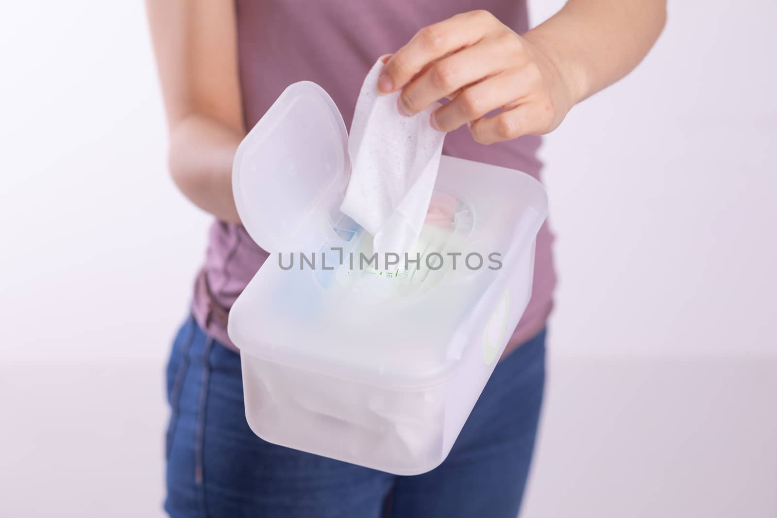Wet wipes are universal an practical: woman hand take one wipe from big plastic box package for cleaning, home, indoor