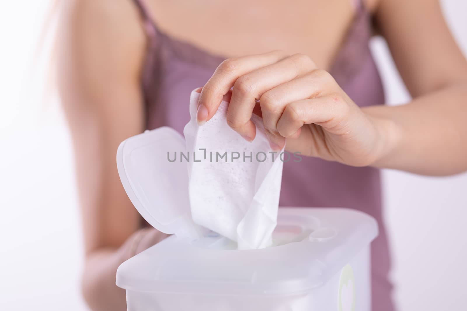 Wet wipes are universal an practical: woman hand take one wipe from big plastic box package for cleaning, home, indoor