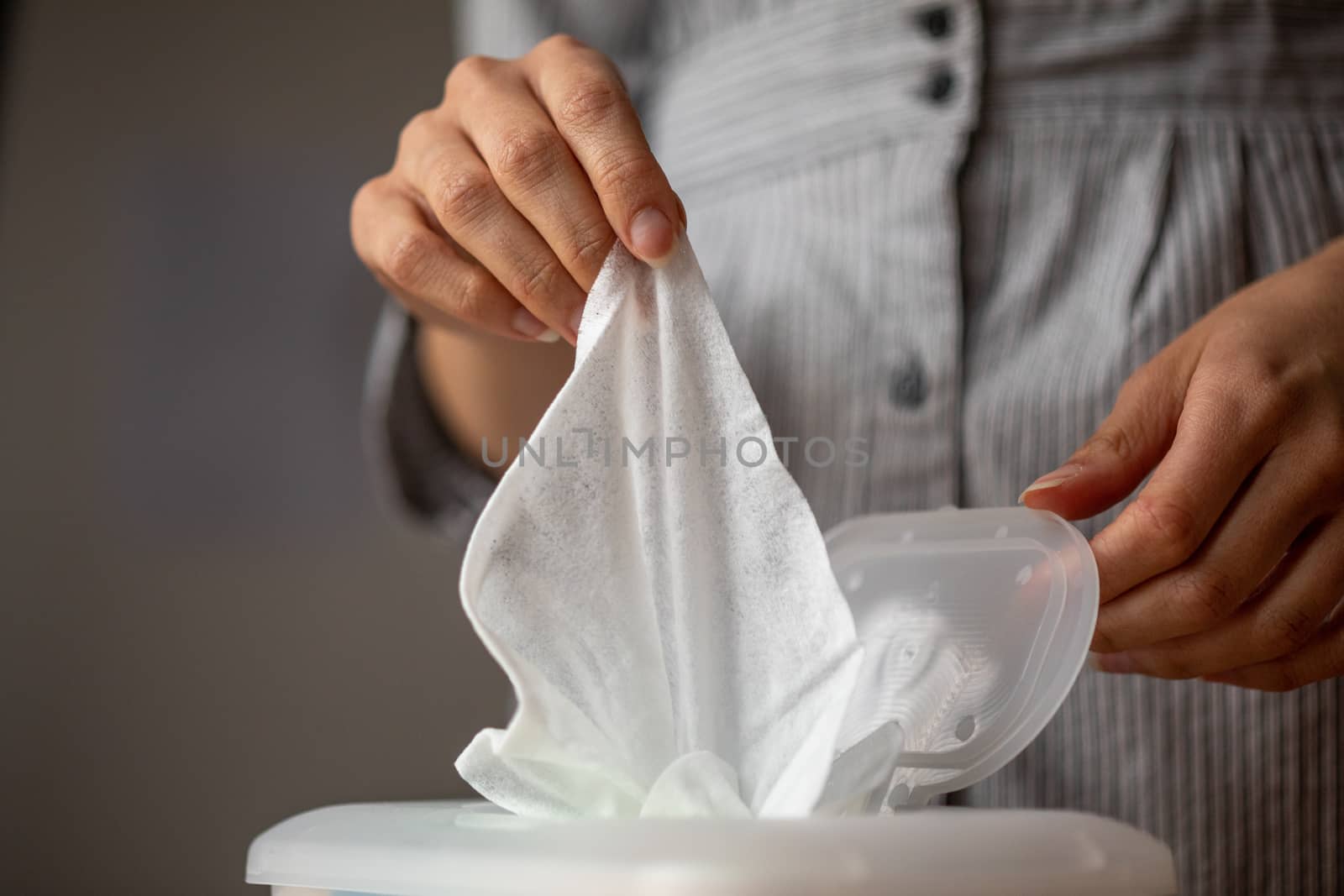 Wet wipes are universal an practical: woman hand take one wipe from big plastic box package for cleaning, home, indoor