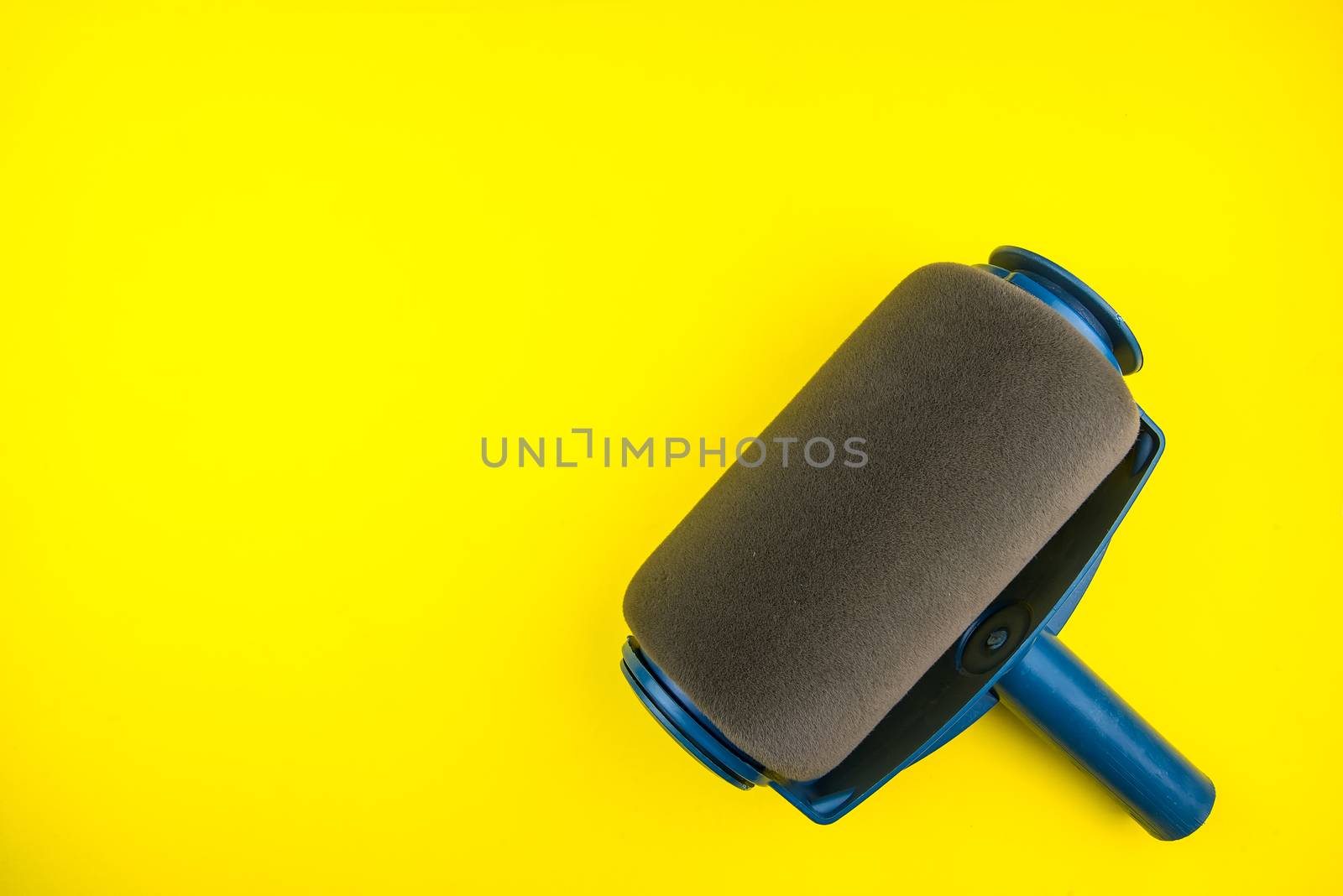 Top view of Paint roller on yellow background with copy space, minimalistic style