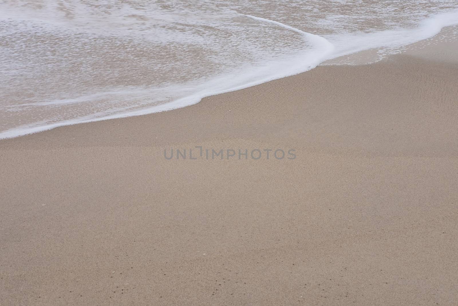 Wave of the sea and white clean foam on the sandy beach with Copy space.