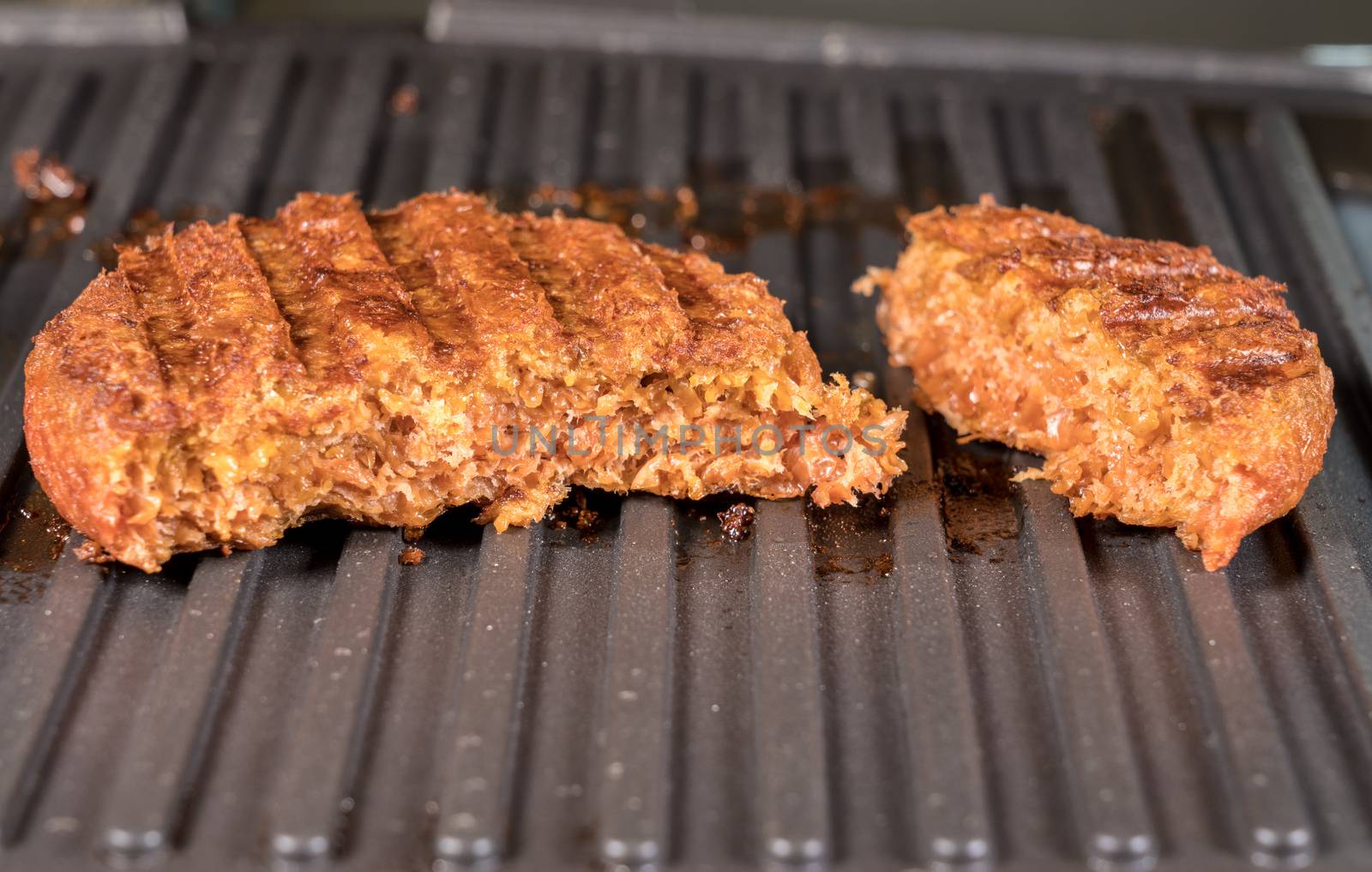 Close shot of the meat like plant-based patties for vegetarian beef burgers being grilled on hot griddle