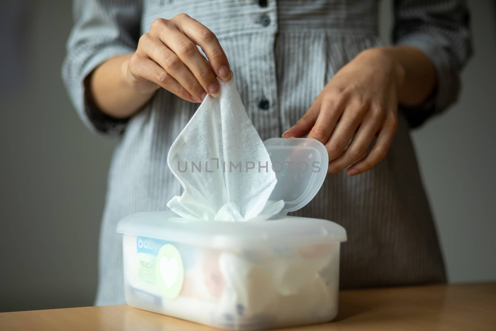 Wet wipes are universal an practical: woman hand take one wipe from big plastic box package for cleaning, home, indoor
