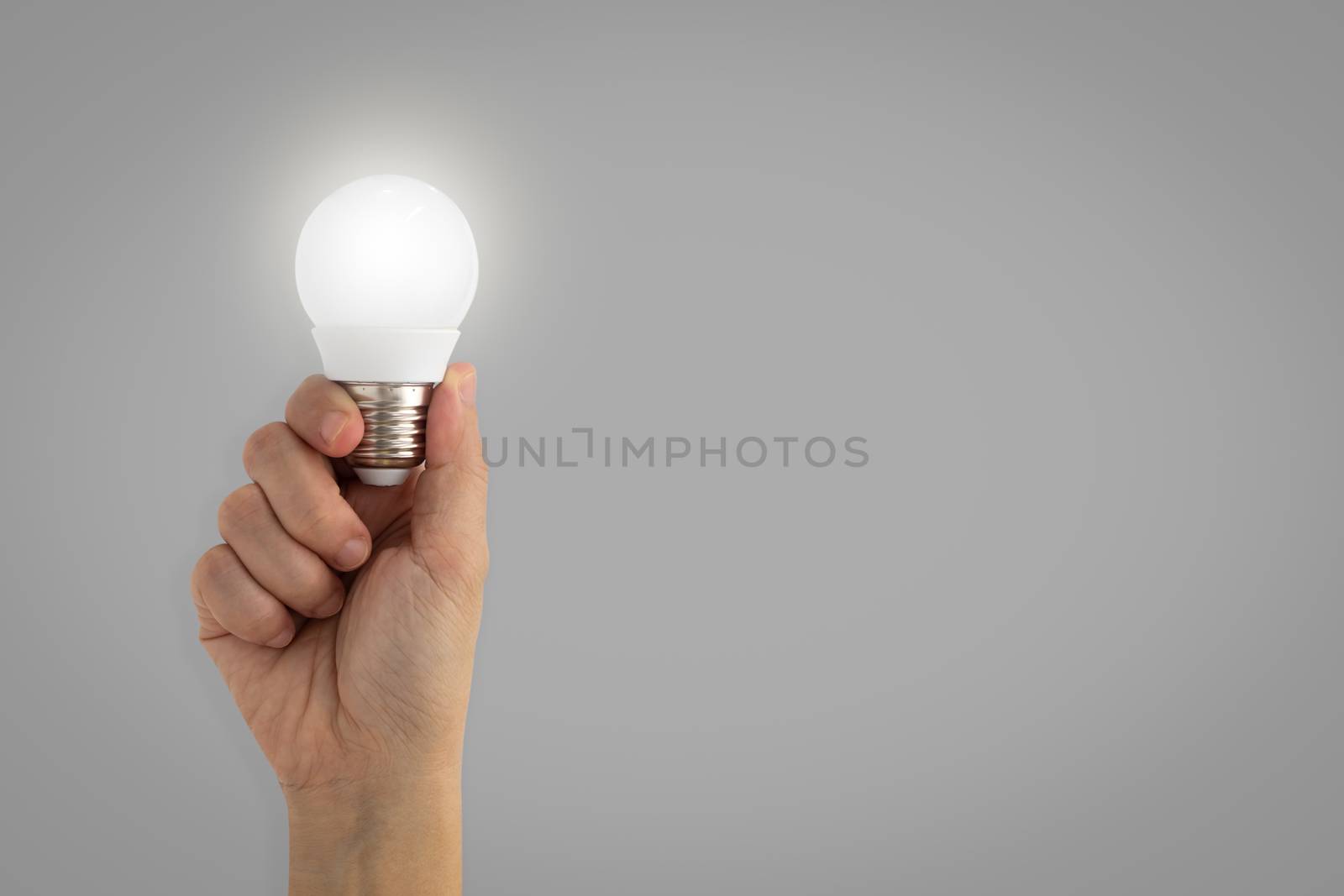 Hand holding illuminated light bulb, idea, inspiration concept by feelartfeelant