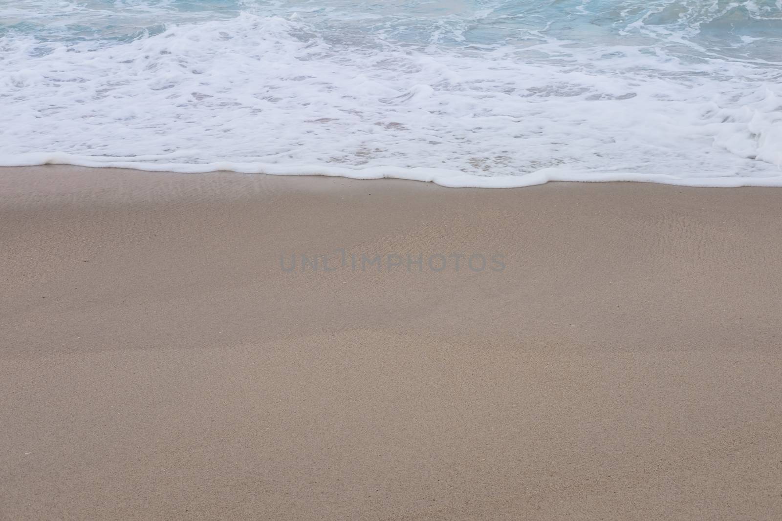 Wave of the sea and white clean foam on the sandy beach with Copy space.