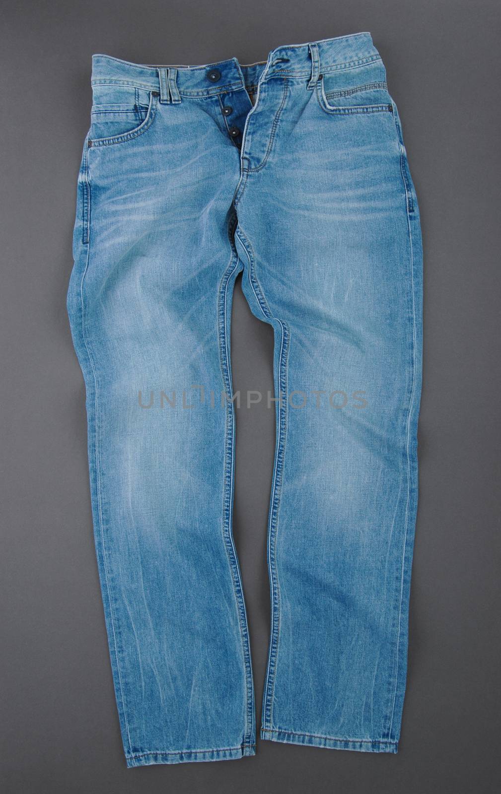 fashionable denim pants on grey background, top view