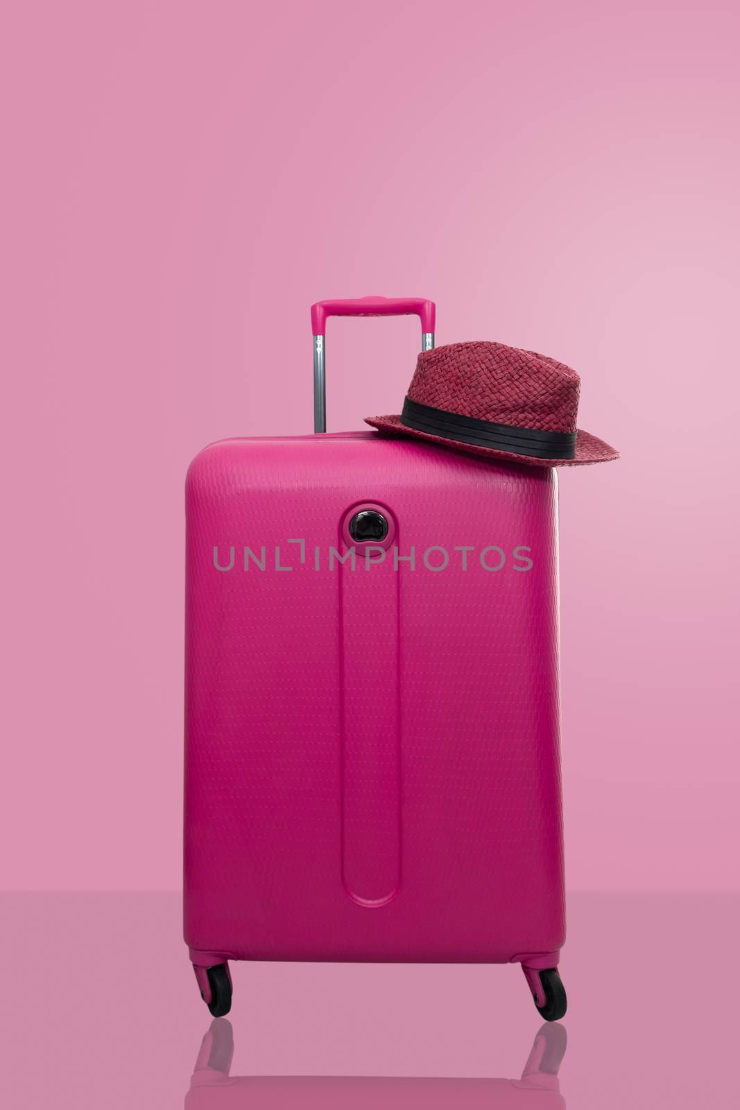 Pink suitcase with hat  on pastel pink background. travel concep by feelartfeelant