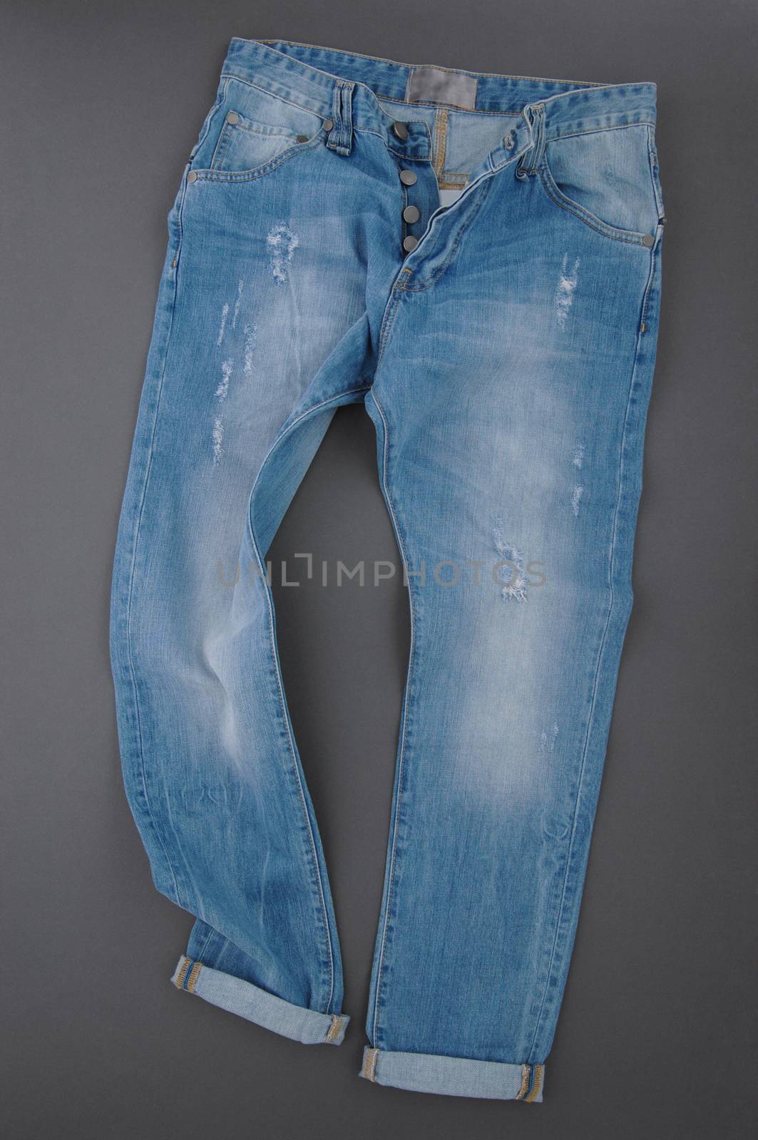 fashionable denim pants on grey background, top view