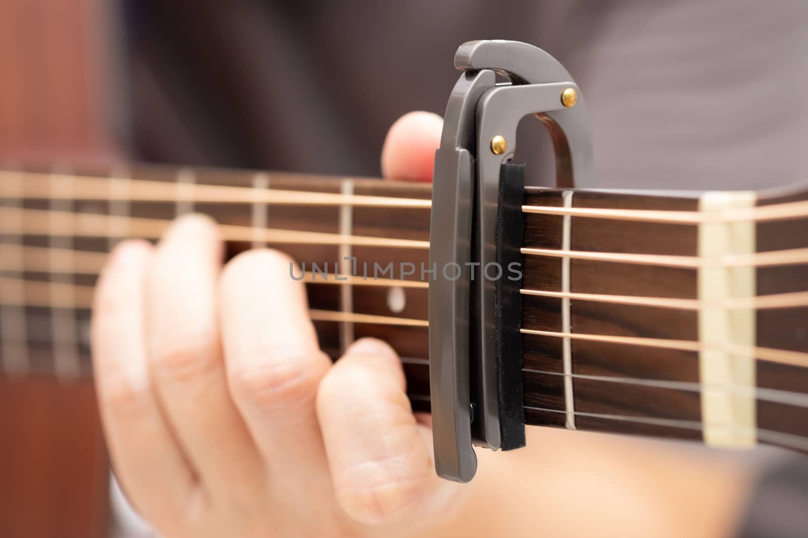 Close up-The hands are adjusting the capo to adjust the sound of the guitar.