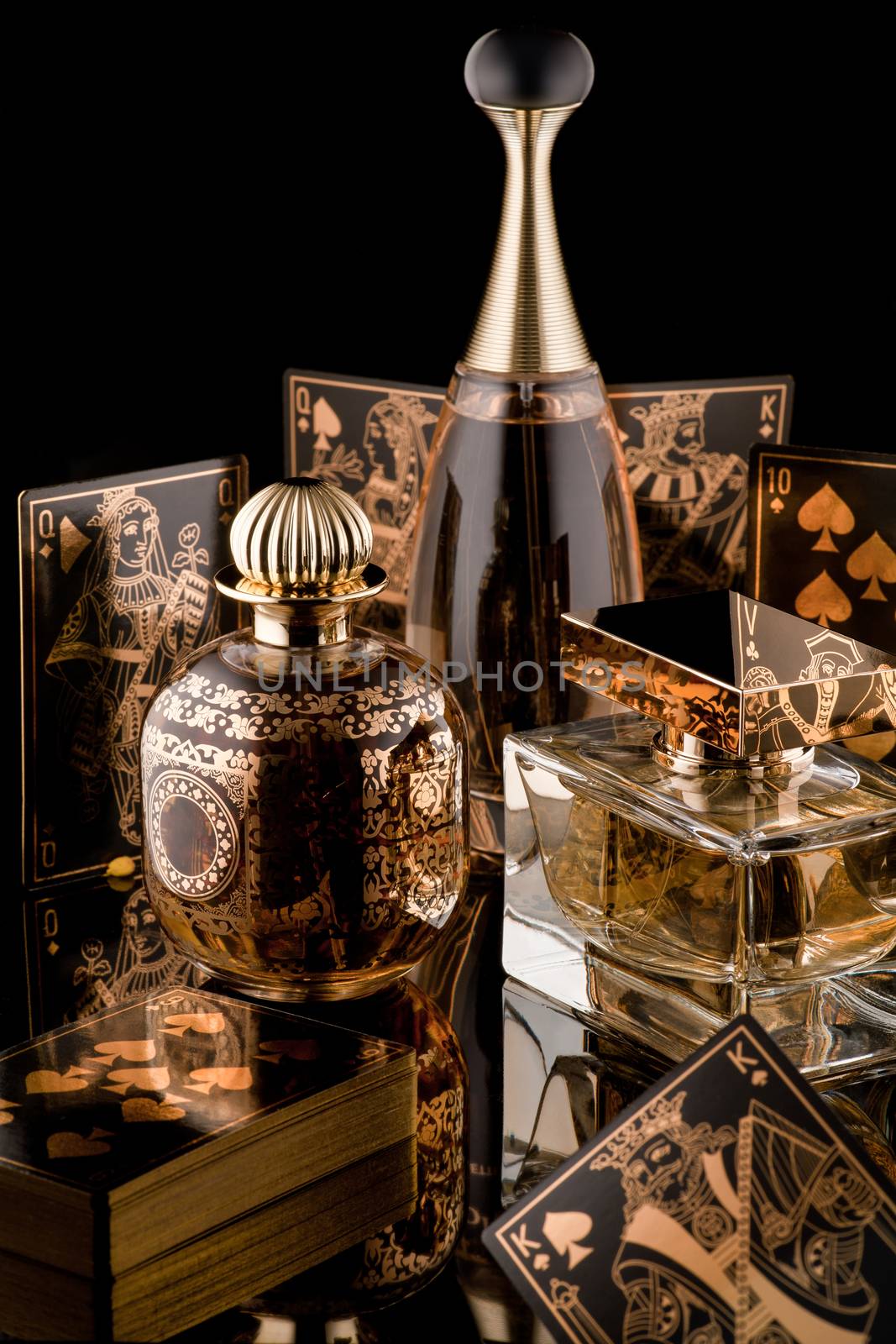 composition of luxurious women's perfume and playing cards with reflection on a black background