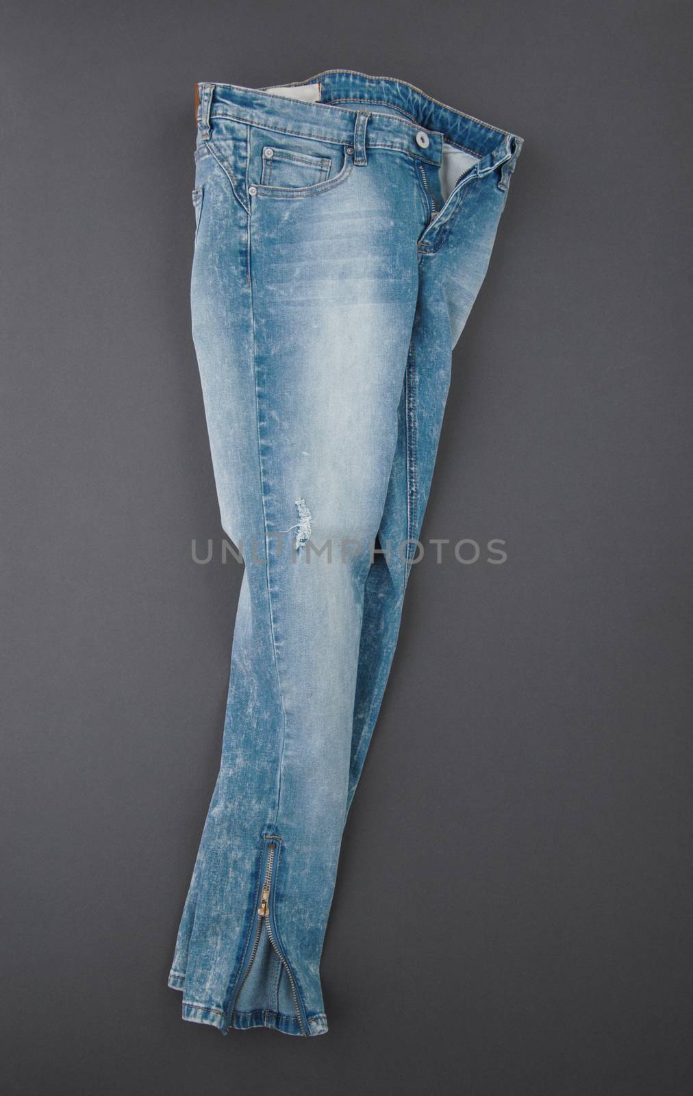 fashionable denim pants on grey background, top view