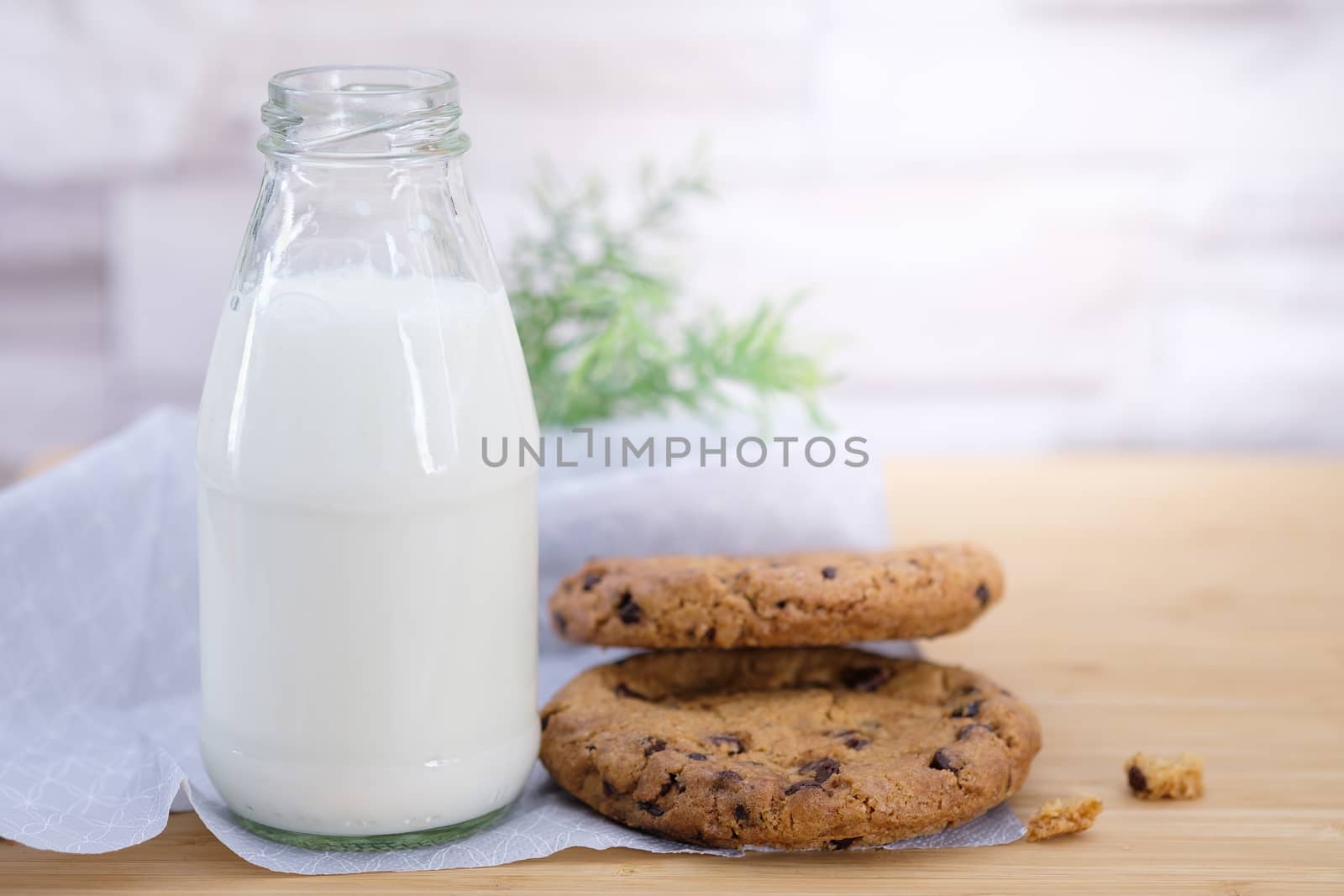 Chocolate chip cookies and a bottle of milk on a  wooden table, Vintage look.