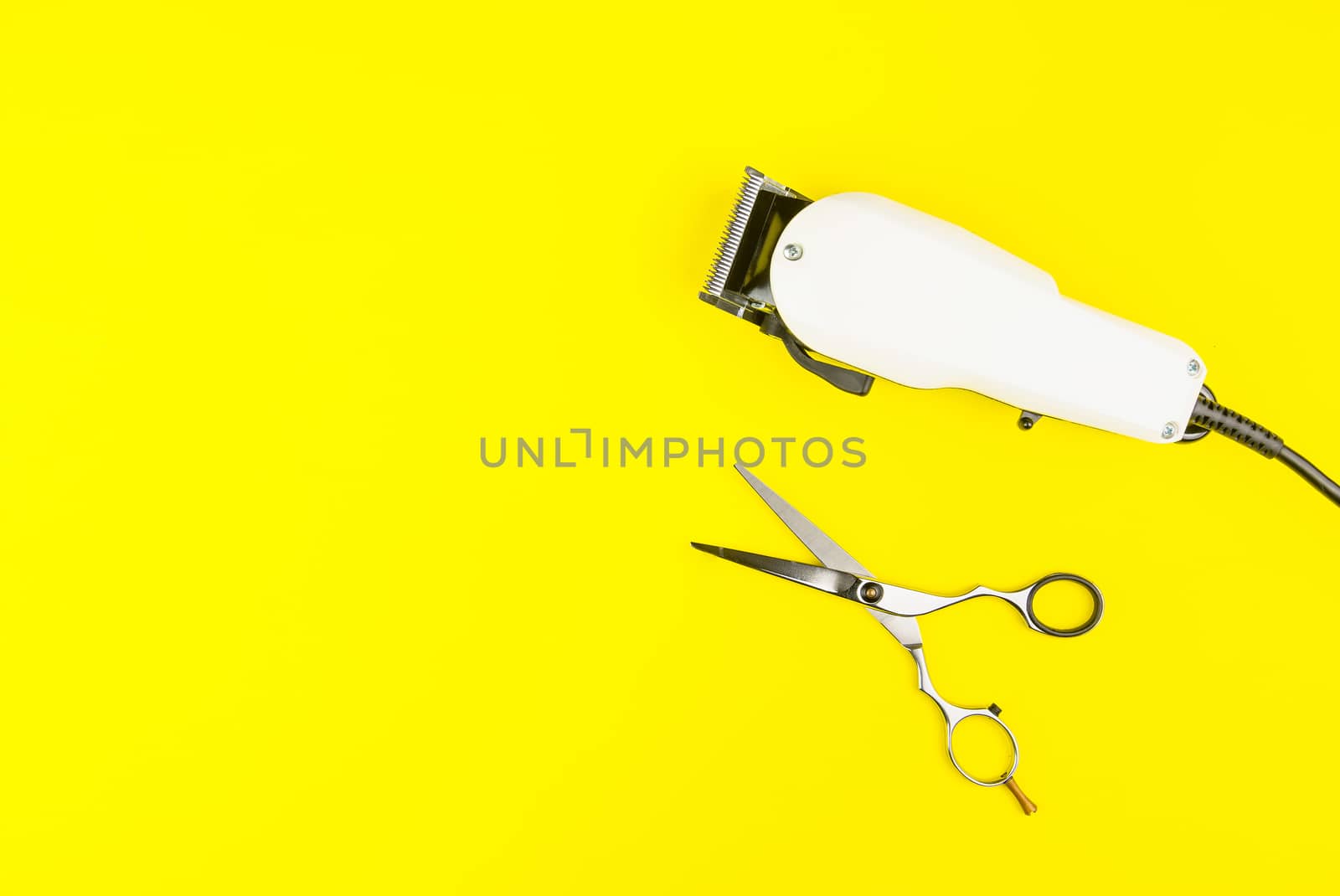Stylish Professional Barber Scissors and White electric clippers on yellow background. Hairdresser salon concept, Hairdressing Set. Haircut accessories. Copy space image, flat lay