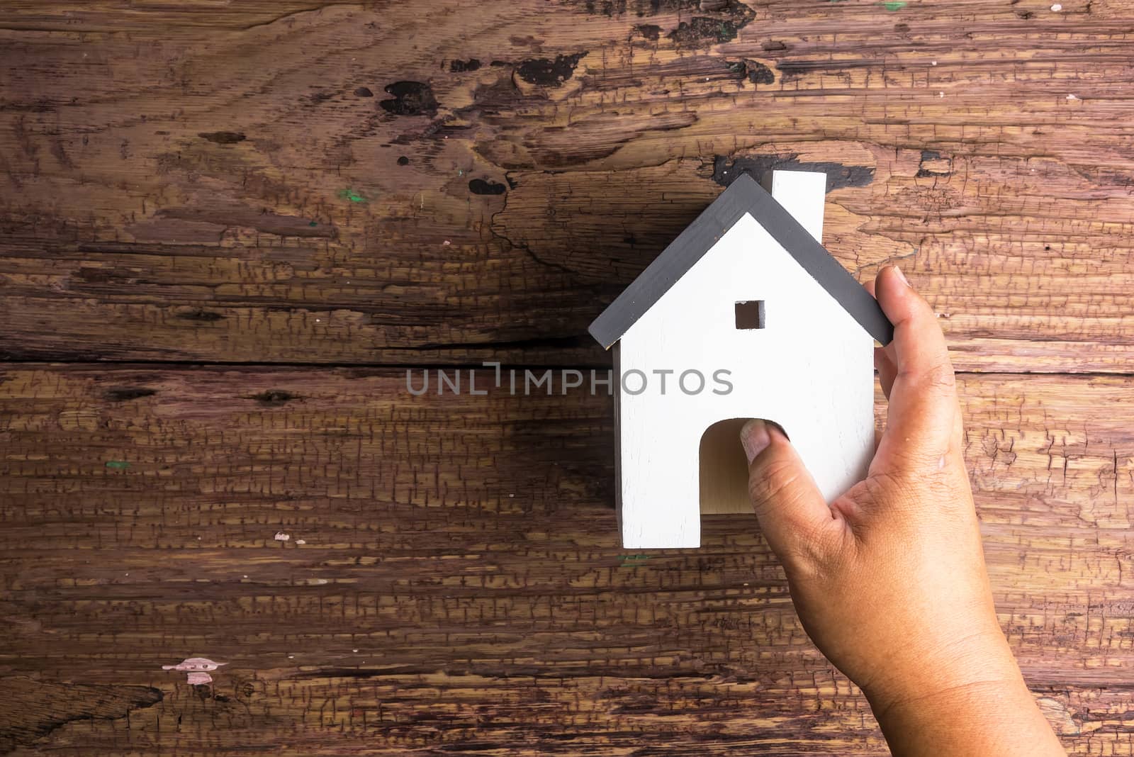 Man's hand holding wooden house toy on wooden background with copy space.Real estate concept, New house concept, Finance loan business concept.