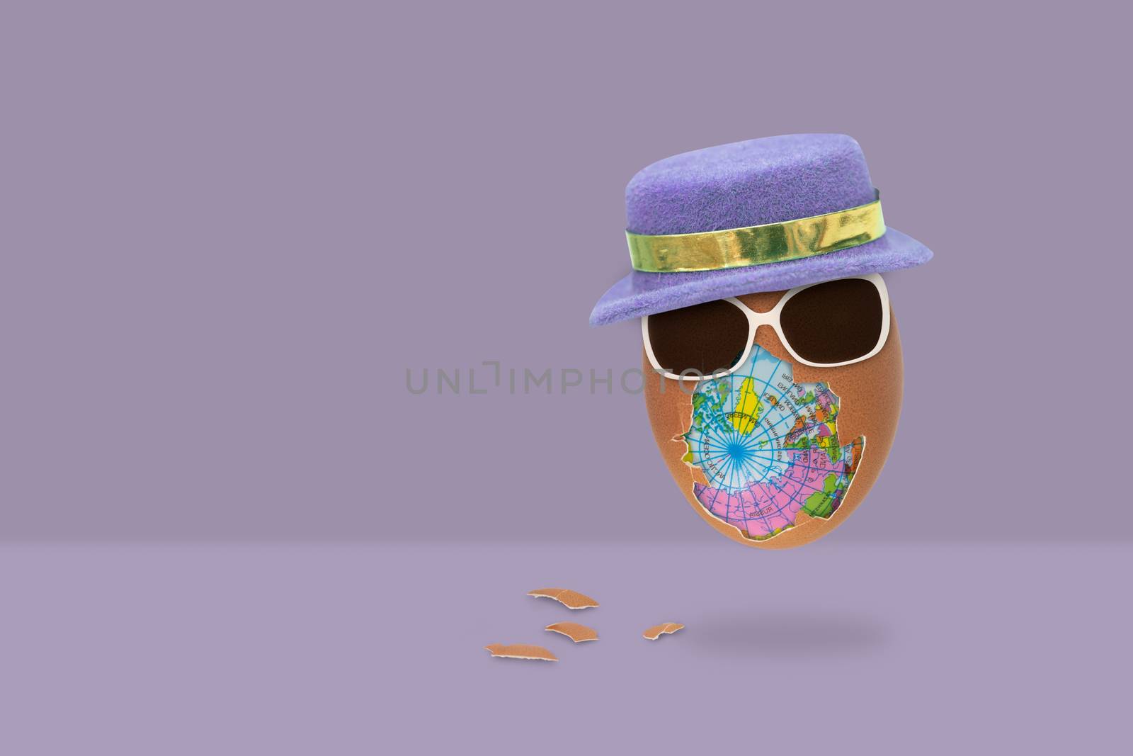 The shelled egg has an globe inside with glasses and hat is flying on purple background. Easter concept.