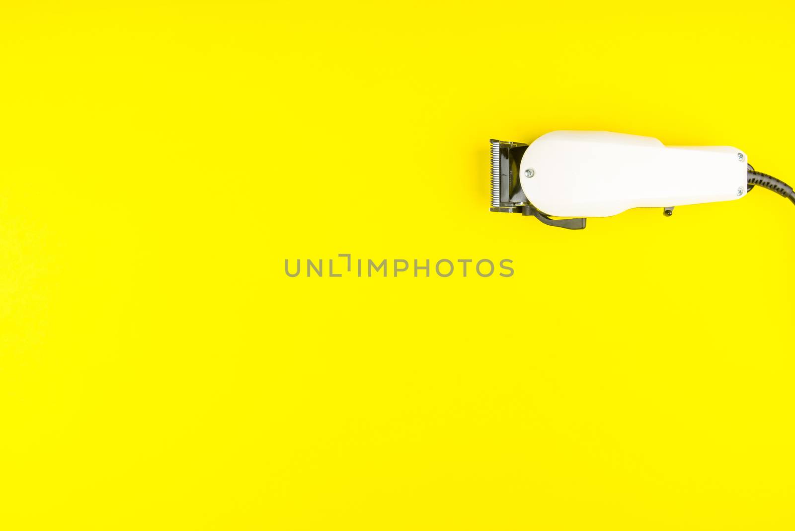 White electric clippers barber on yellow background. Hairdresser by Bubbers