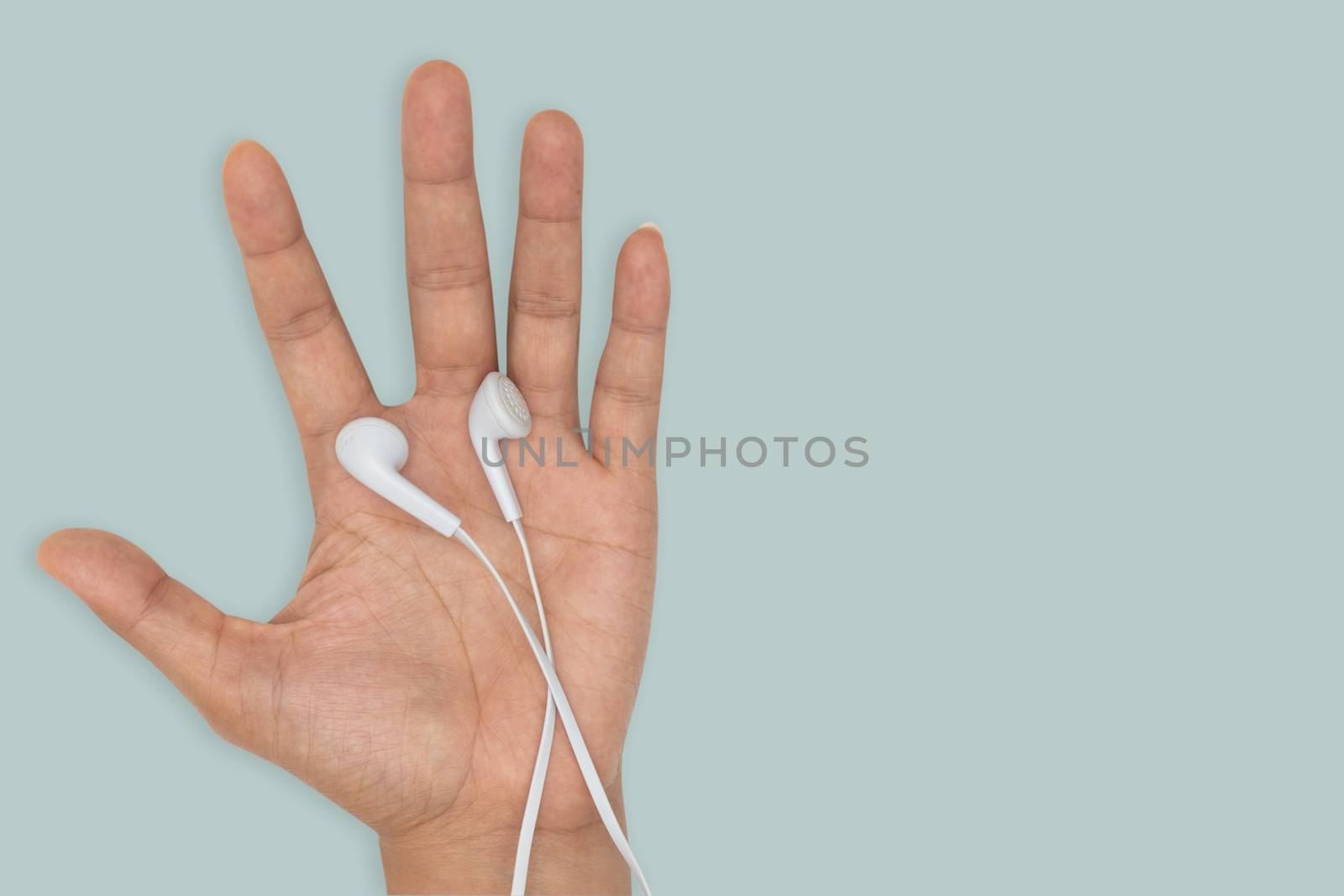 Top view-White headphones on human hand isolated on green backgr by feelartfeelant