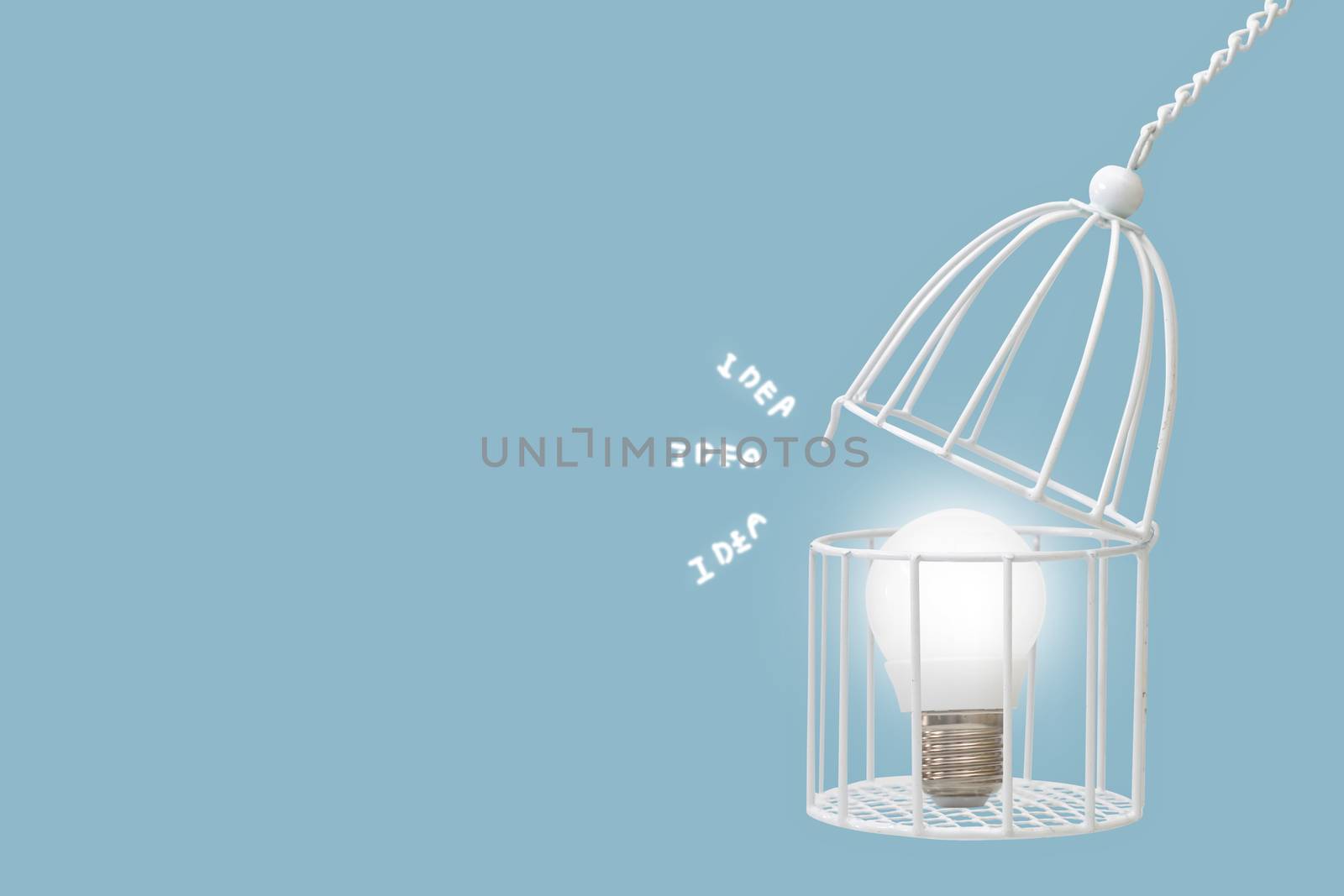 Lamp bulb in bird cage isolated on blue background, minimal idea concept.
