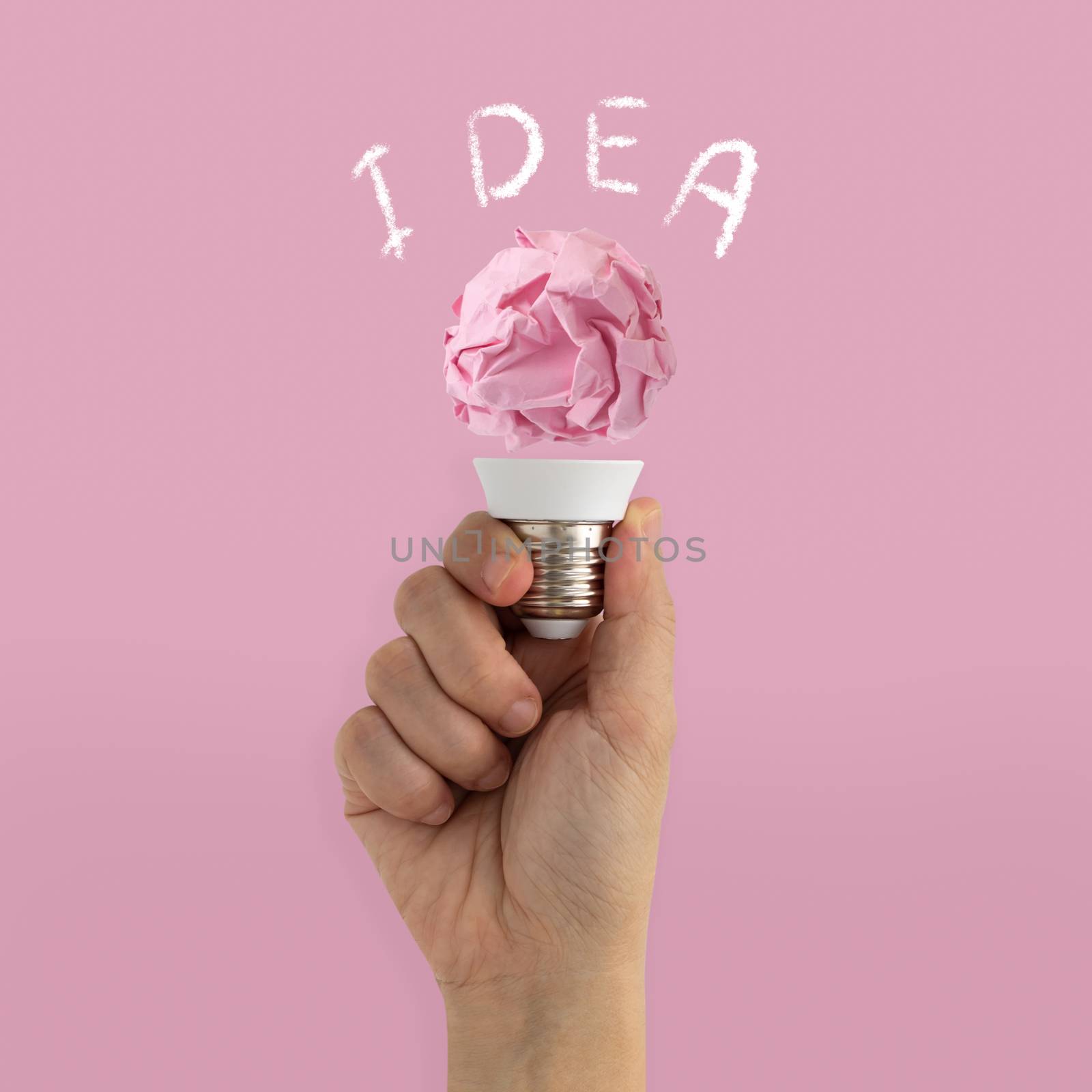Hand holding paper illuminated light bulb on pink background, idea, inspiration minimal concept.