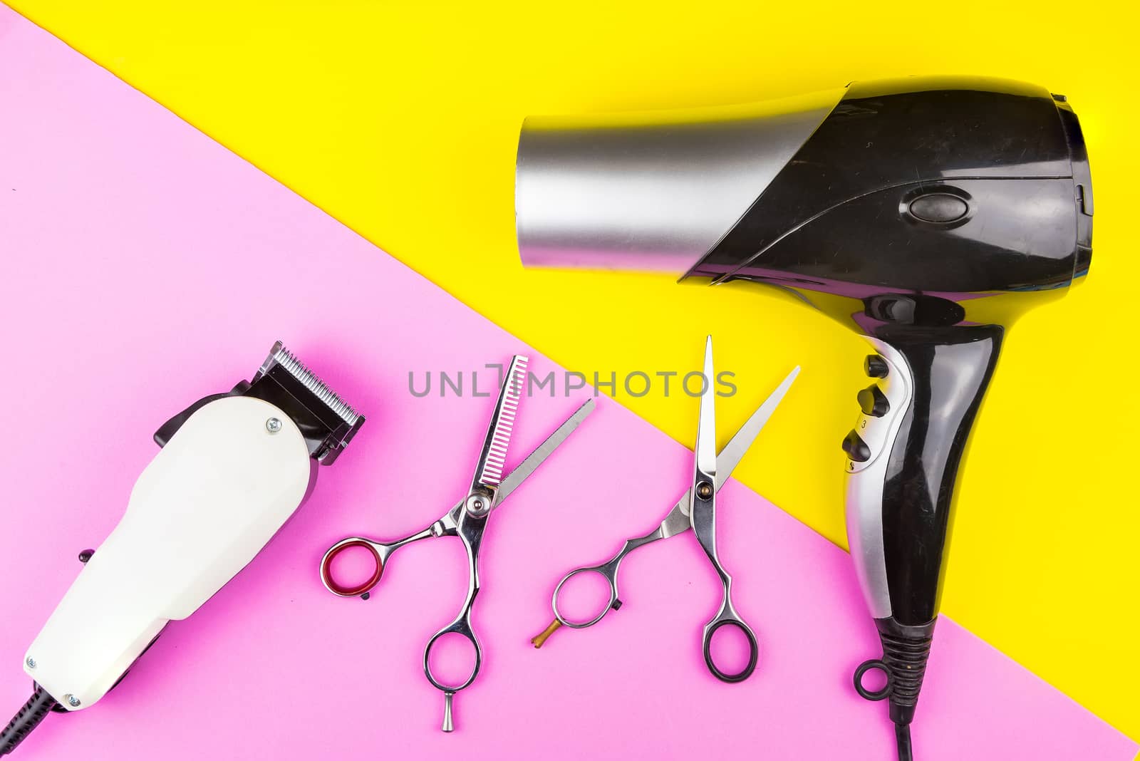 Stylish Professional Barber Scissors, White electric clippers and hair dryer on yellow and pink background. Hairdresser salon concept, Hairdressing Set. Haircut accessories. Copy space image, flat lay