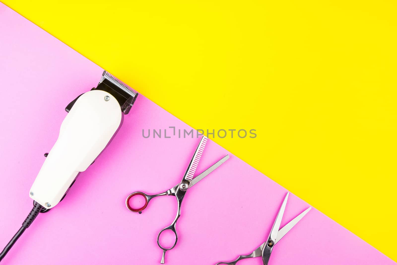 Stylish Professional Barber Scissors and White electric clippers on yellow and pink background. Hairdresser salon concept, Hairdressing Set. Haircut accessories. Copy space image, flat lay