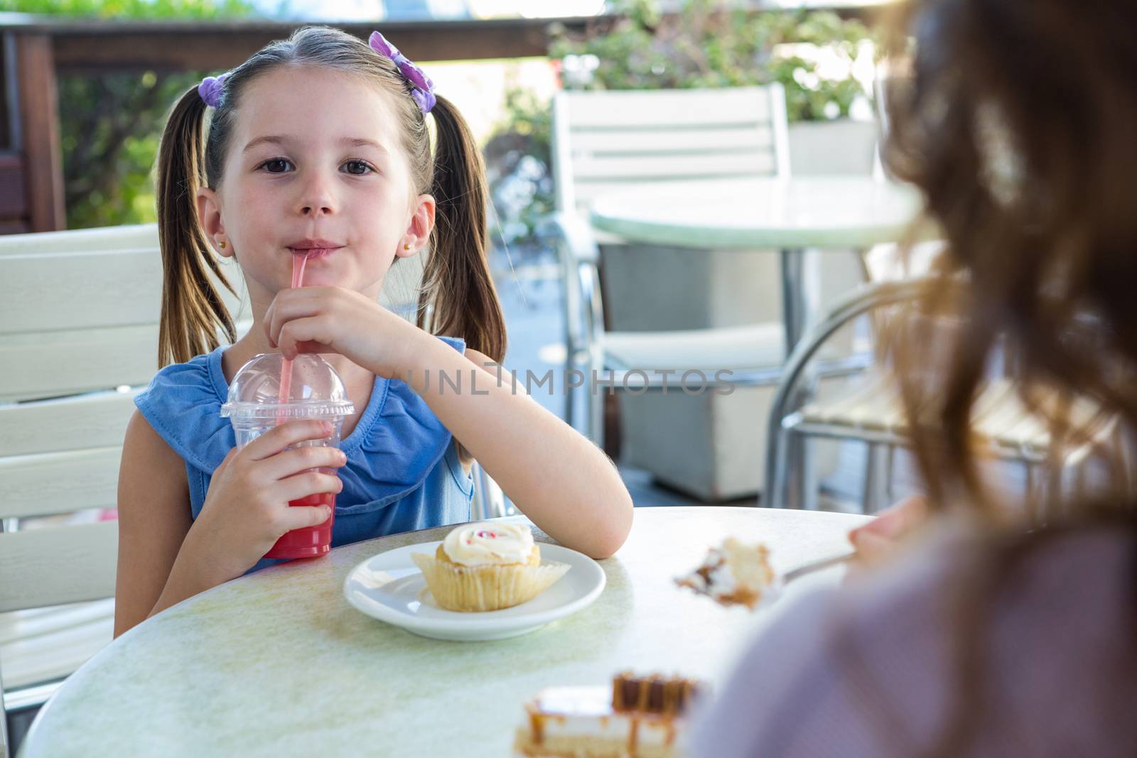 Mother and daughter enjoying cakes at cafe terrace on a sunny day