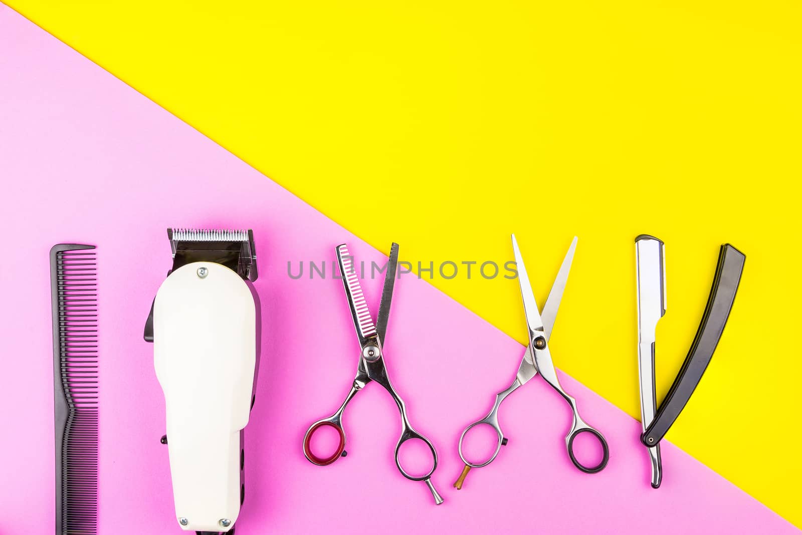 Stylish Professional Barber Scissors and White electric clippers on yellow and pink background. Hairdresser salon concept, Hairdressing Set. Haircut accessories. Copy space image, flat lay