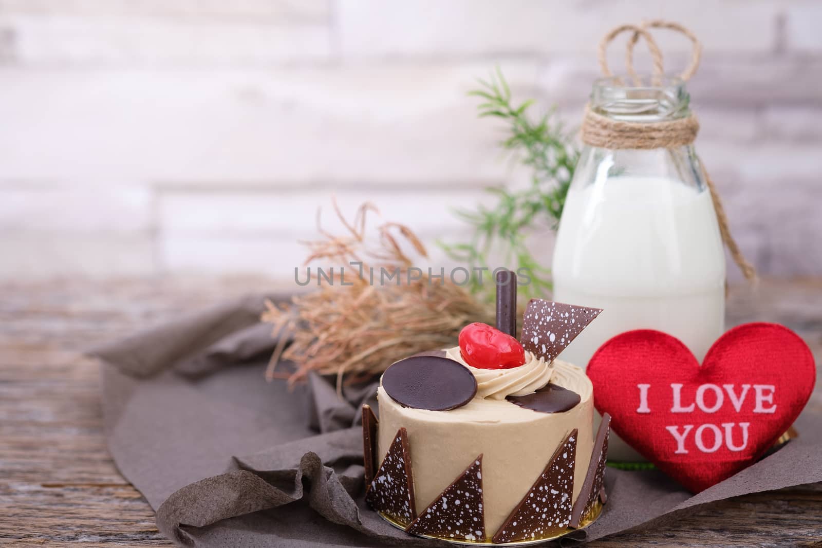 Cake and a bottle of milk on a  wooden table in warm light, Vintage tone, Space to write, Valentine concept.