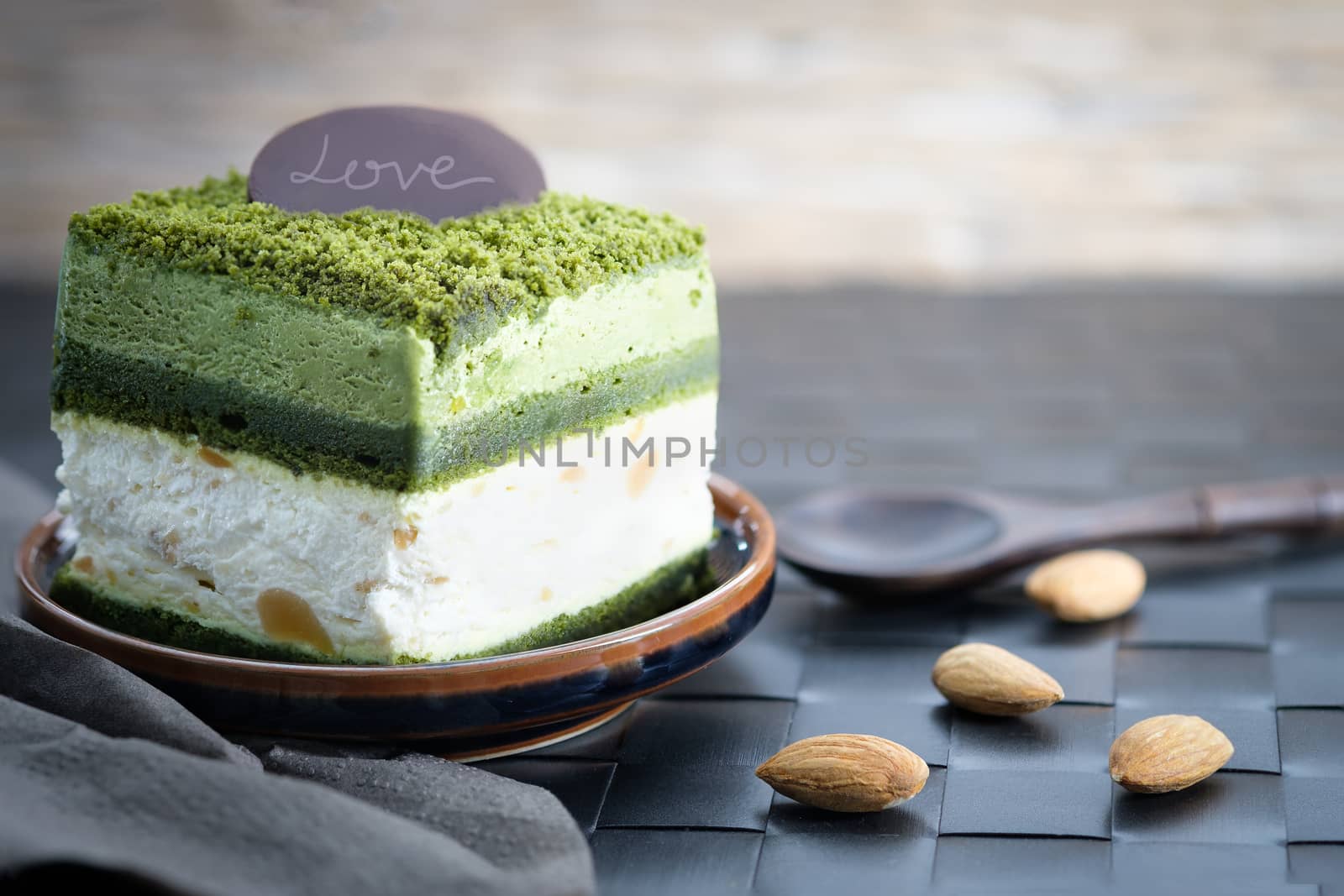 Macadamia cake with greentea and white cream on wooden table, close up, space to write.