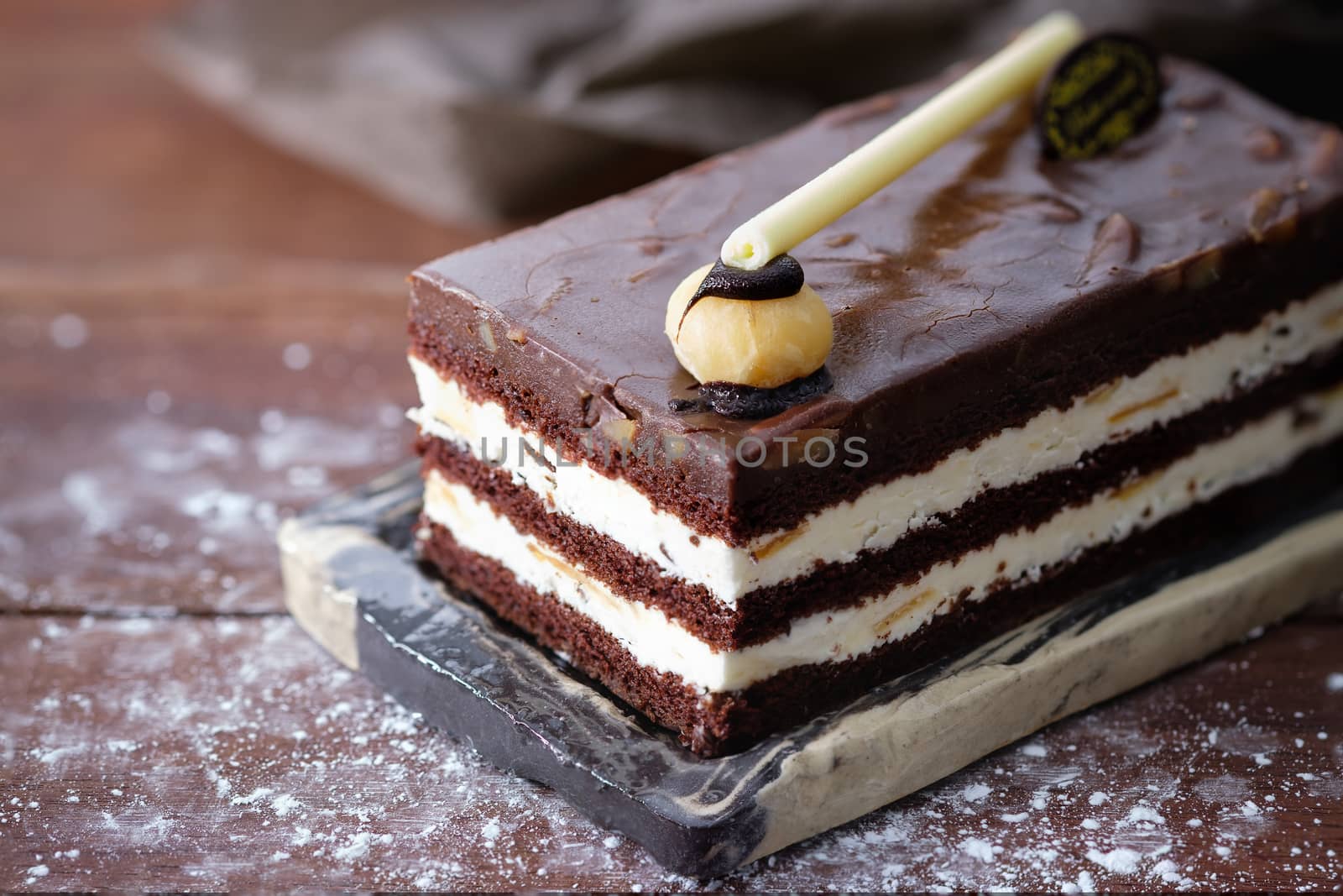 Chocolate cake with white cream on wooden table, close up, space to write.