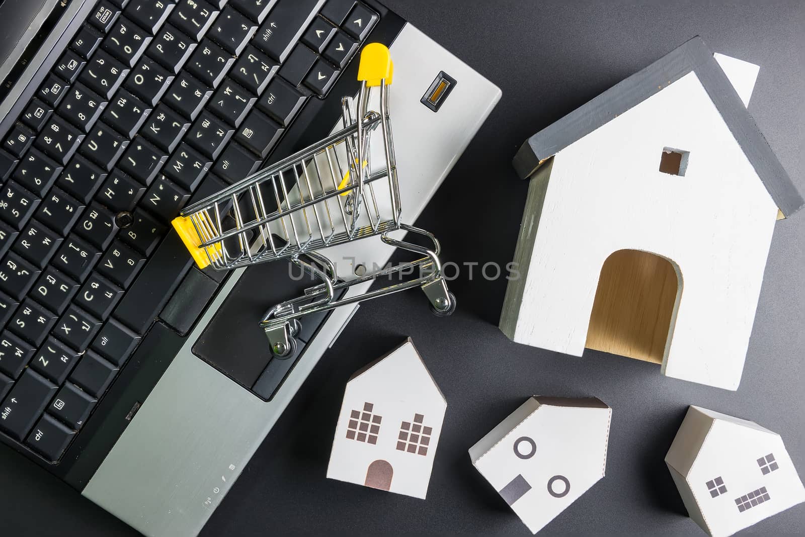 Shopping cart and  paper hose model on laptop notebook.Online shopping concept.Real estate concept, New house concept.Buying a house.