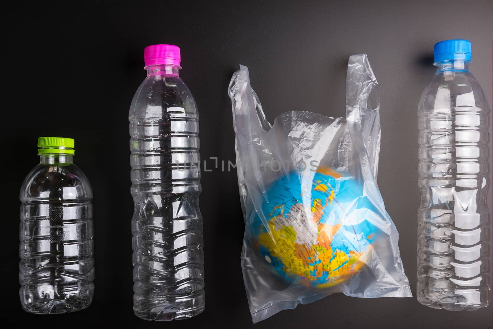 Earth world globe and plastic bottle waste on the black background.Saving the planet Earth from plastic bags concept.Global warming.Plastic waste overflows the world