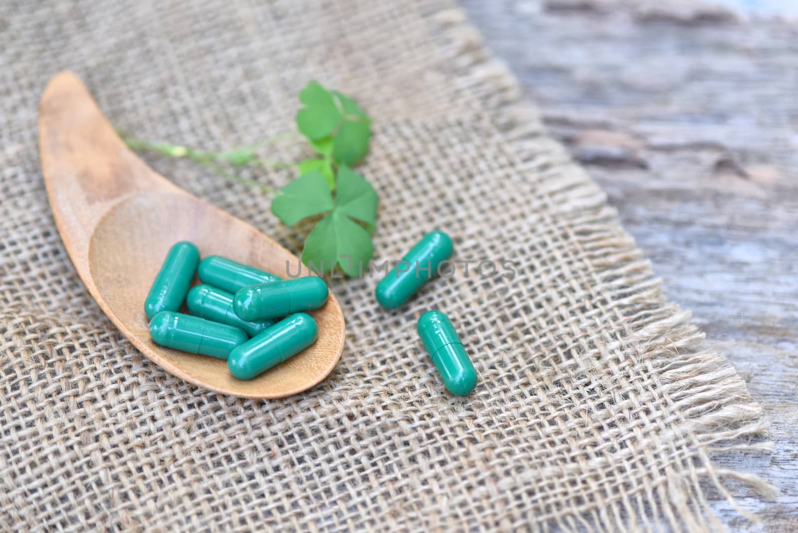 Herbal Medicines / Natural herb capsules Andrographis paniculata in spoon on wooden rustic background and copy space for using in medical background, healthy eating for good life. selective focus